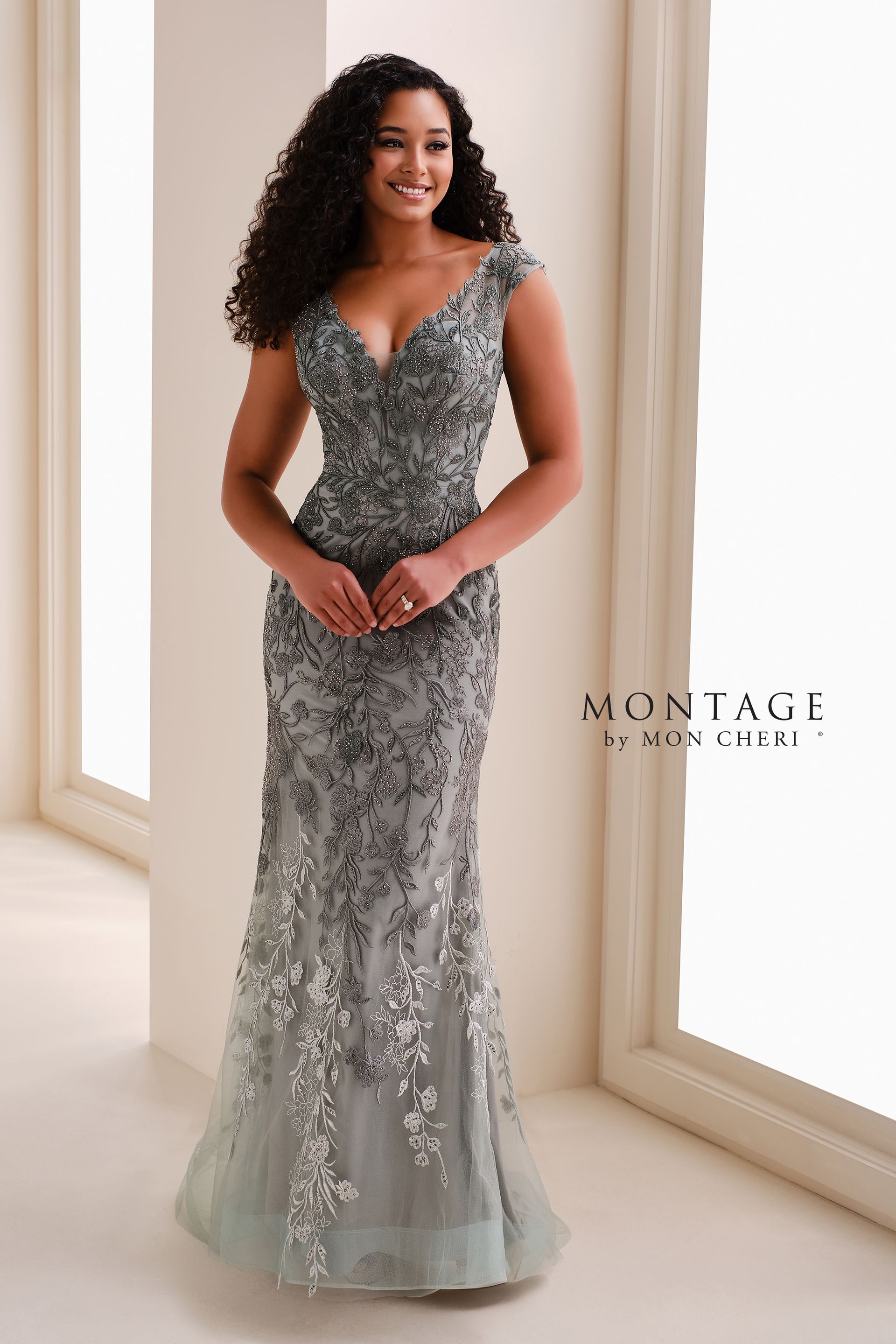 Woman in a silver beaded evening gown standing in a bright studio, with a MONTAIGE logo on the wall