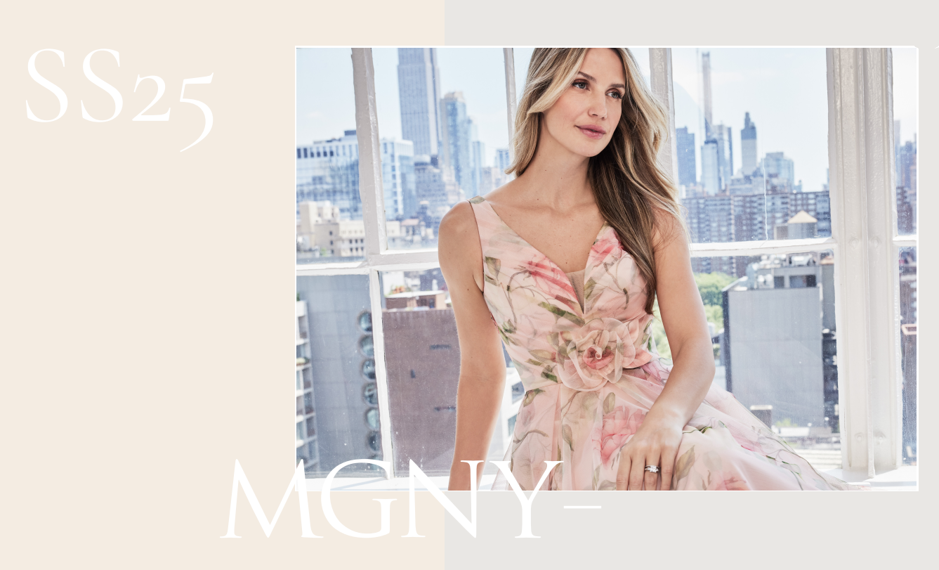 Woman in floral dress, poses by a window overlooking a cityscape.