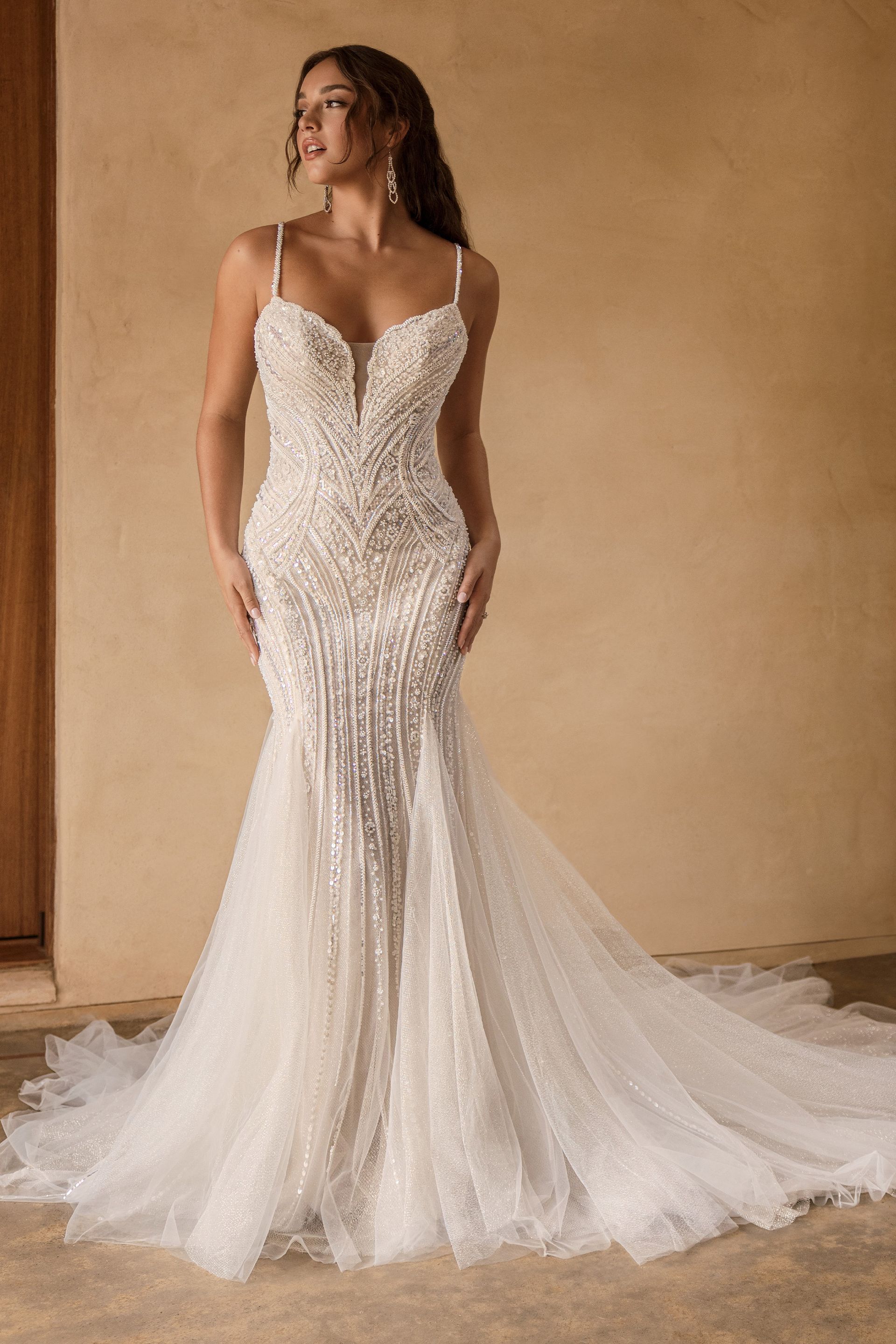 Woman in a white beaded mermaid wedding gown with a train.
