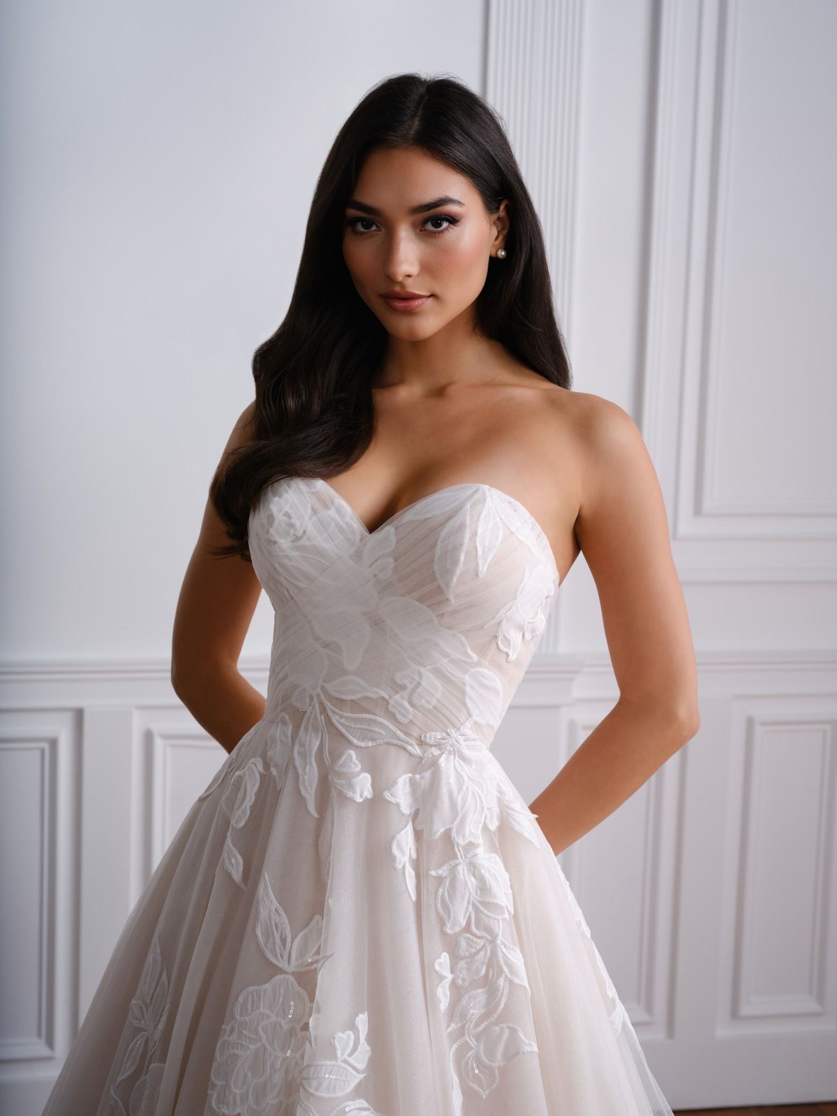 Woman in a strapless white lace dress posing in a bright paneled room.