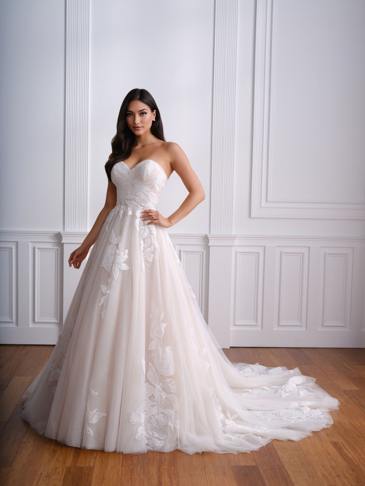 Woman in a strapless white lace dress posing in a bright paneled room.