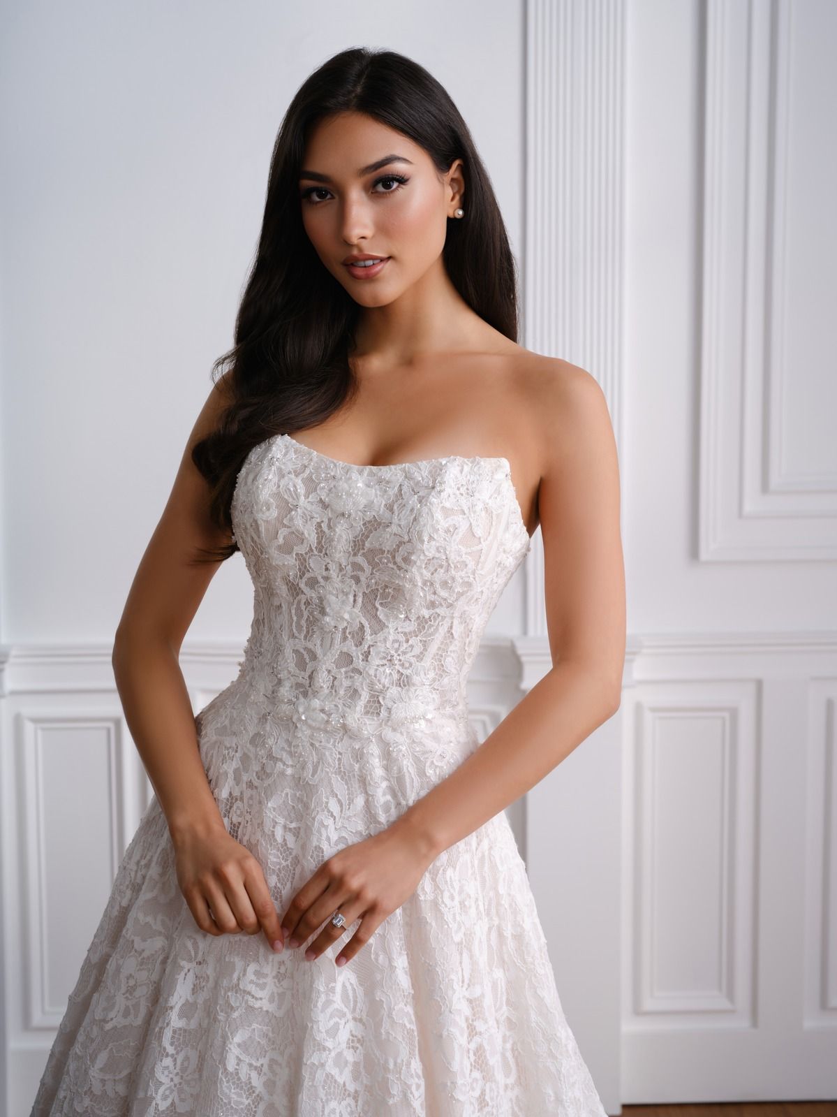 Woman in a strapless white lace gown standing in a bright paneled room.