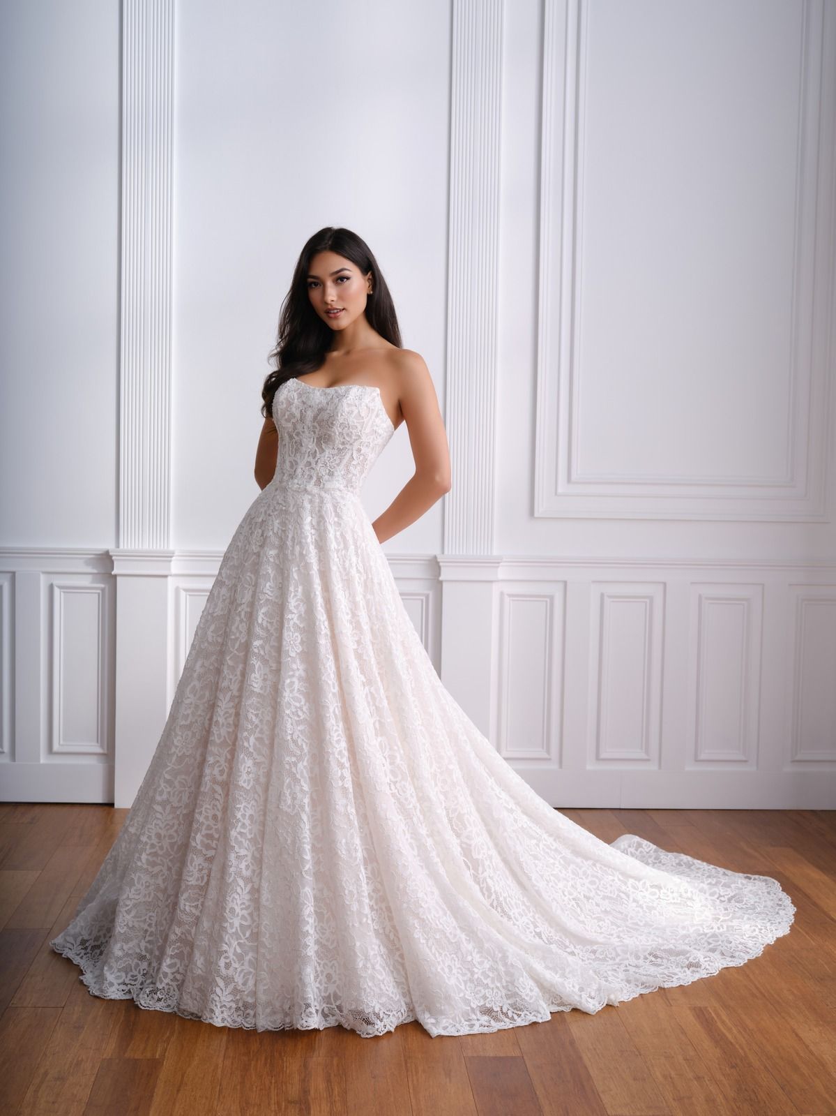 Woman in a strapless white lace gown standing in a bright paneled room.