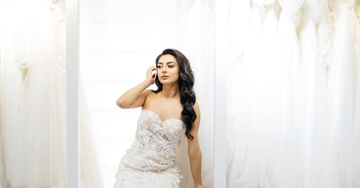 Woman in a white wedding dress talking on the phone in a bridal shop.