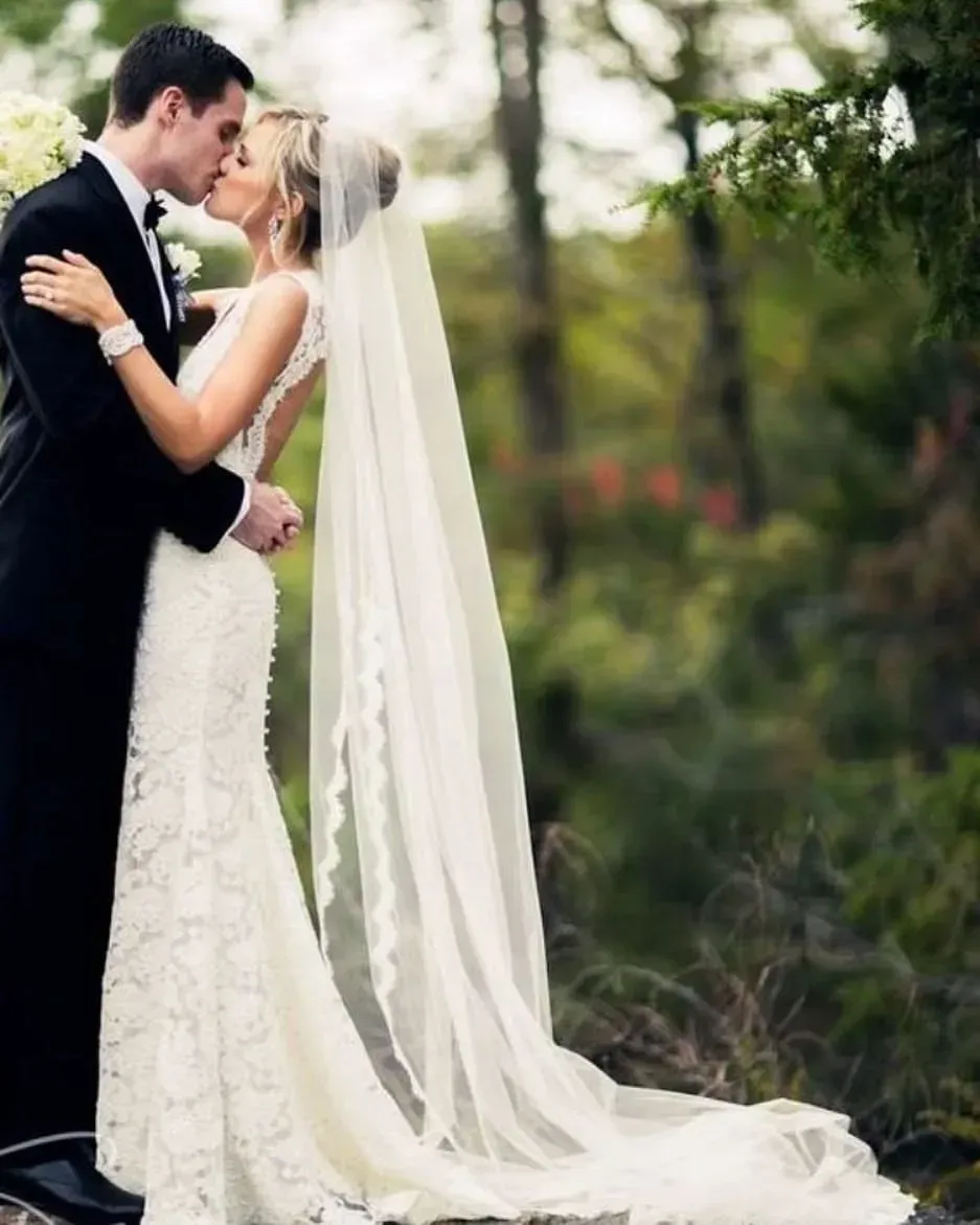 Bride and groom kissing, he in black tuxedo, she in white lace dress and veil, in a forest. Bride and groom kissing, he in black tuxedo, she in white lace dress and veil, in a forest.