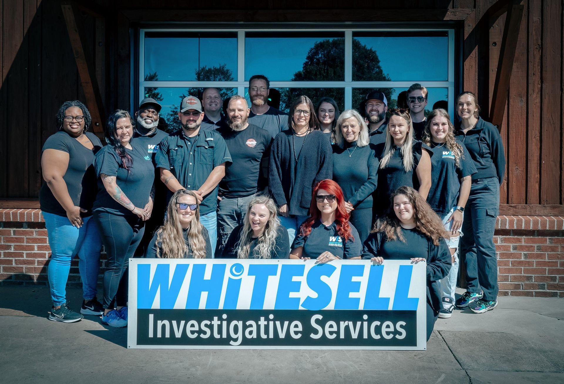 Group of people in front of a building pose with a sign that reads 