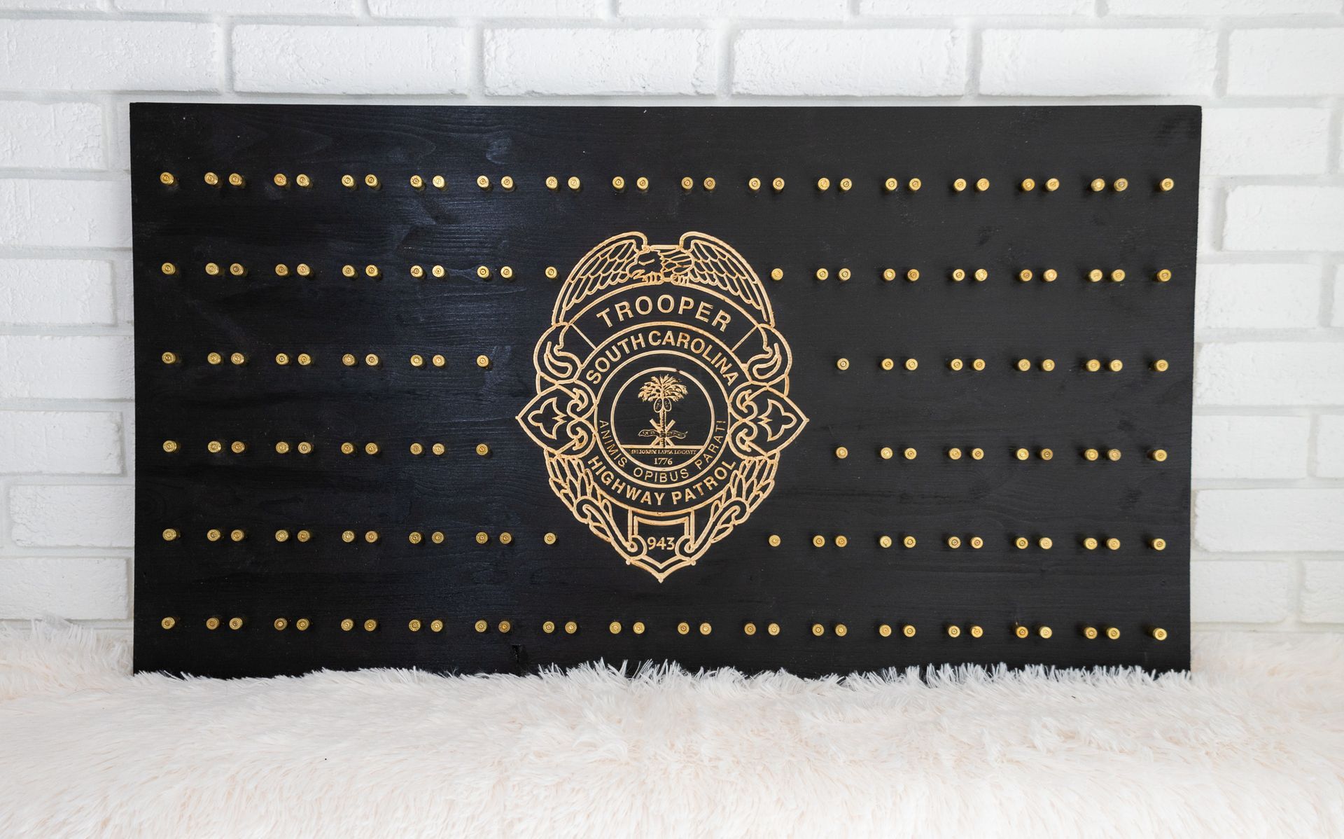Black wooden badge display with gold studs, a gold police badge in the center, and the South Carolina state seal.