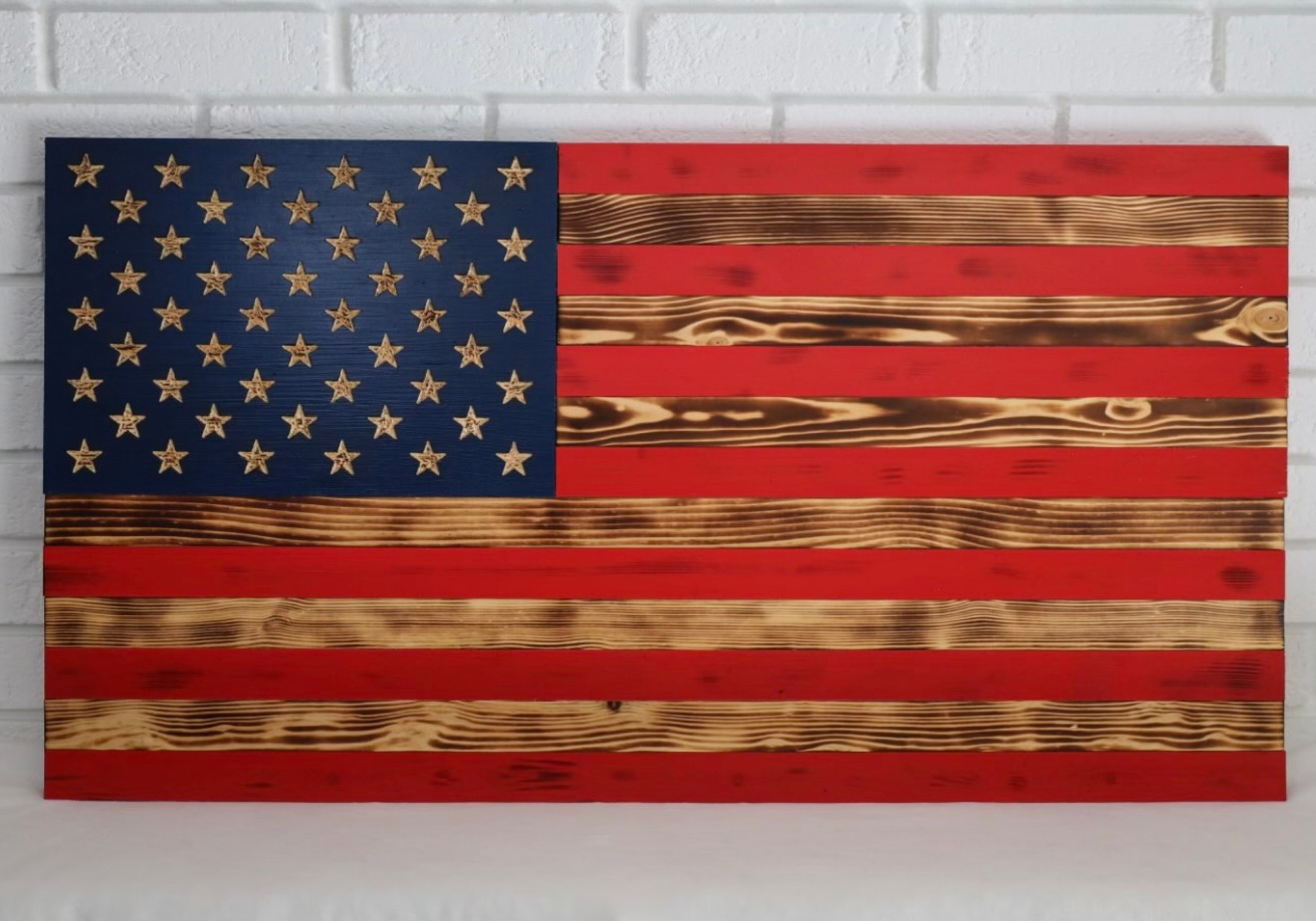 Wooden American flag with red and blue paint, burnt wood stripes, and cutout stars.