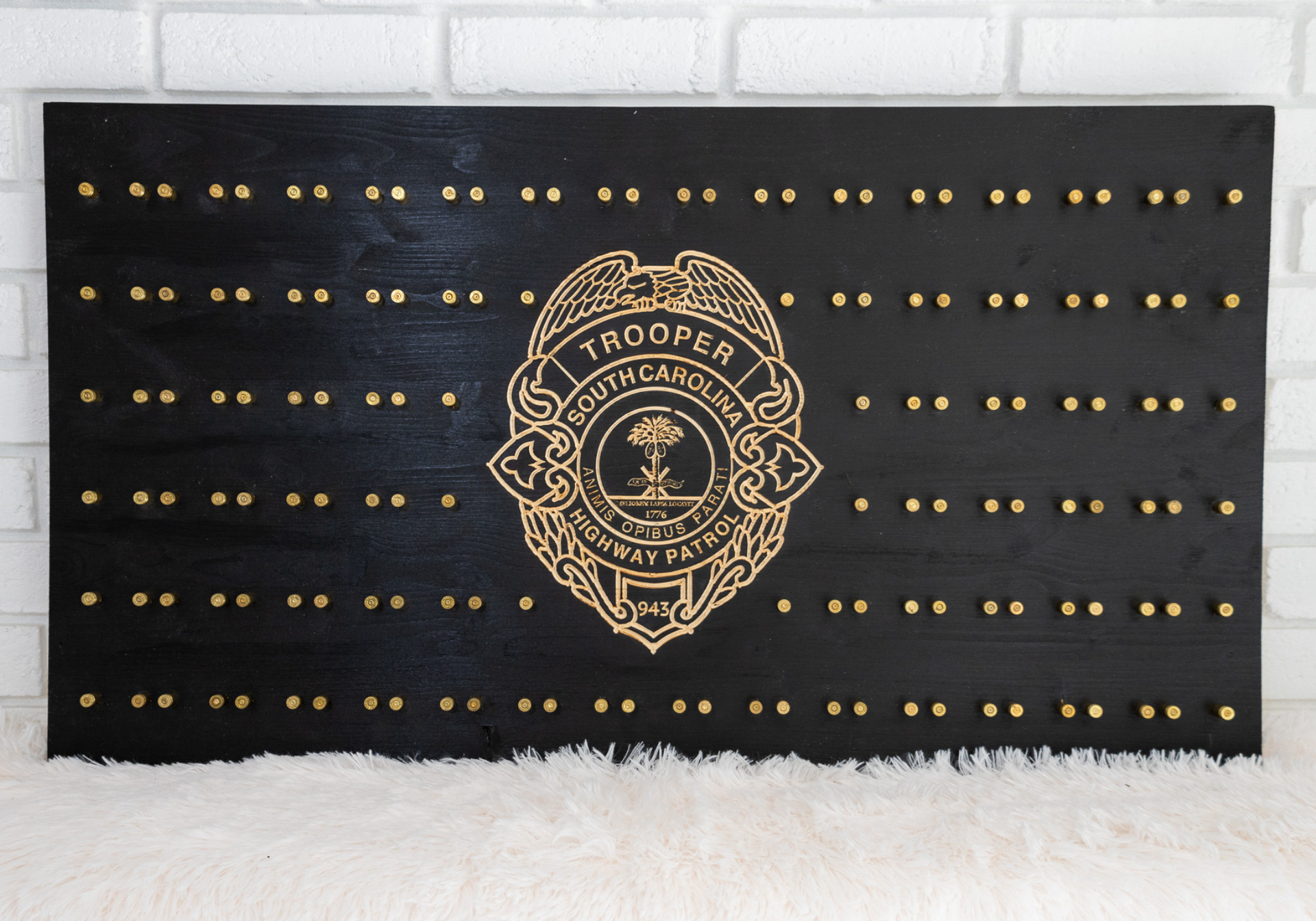 Black wooden sign with gold dots and a police badge, resembling a flag.