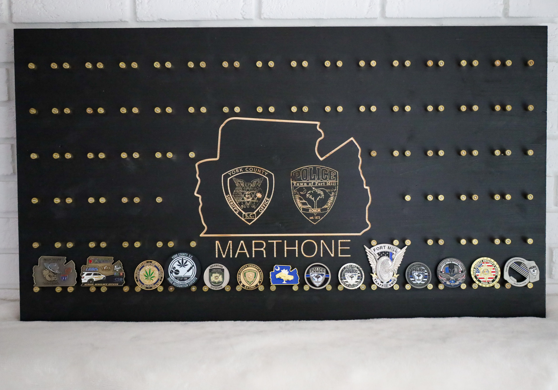 Black display board with pins, challenge coins, gold accents, and a silhouette of a region.
