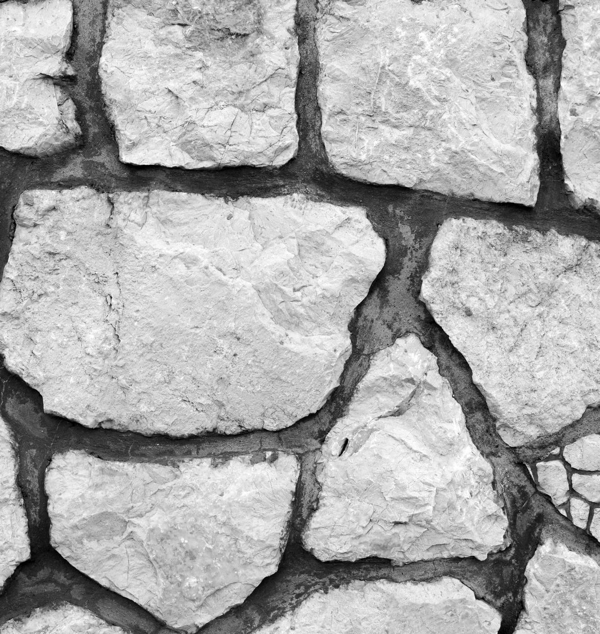 Close-up view of a stone wall, gray stones with dark grout.
