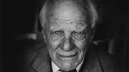 Close-up black and white portrait of an elderly man with wrinkles and a slight smile.