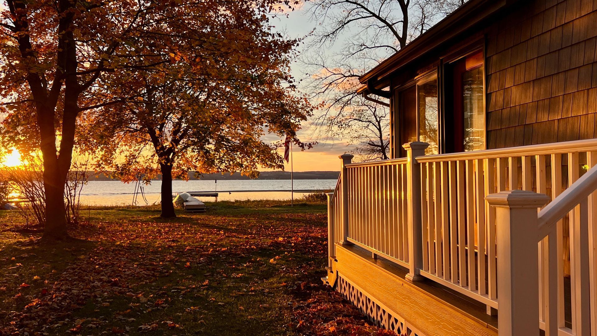 A house with a balcony overlooking a lake at sunset.