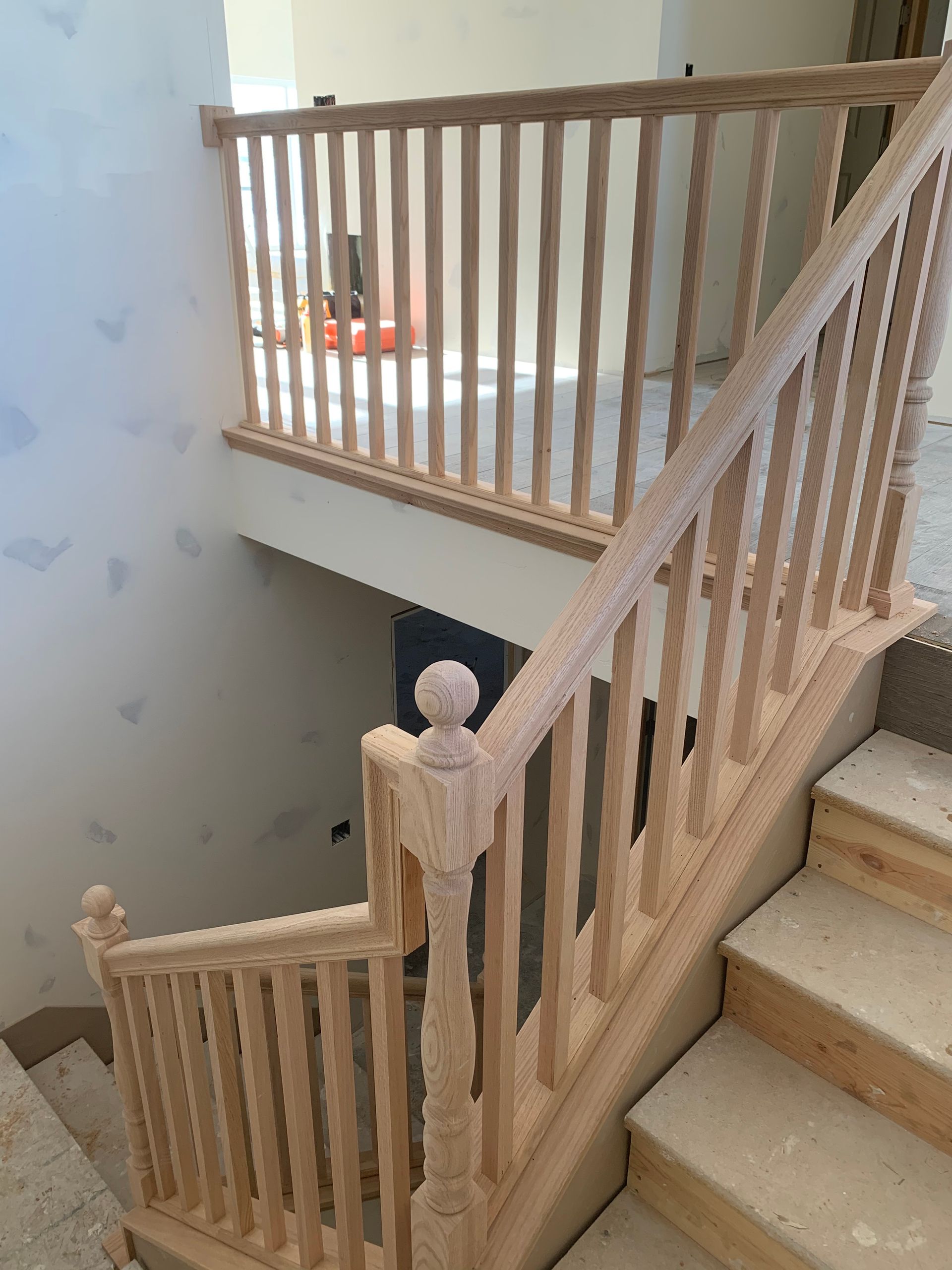 Wooden staircase under construction with railing and balusters.