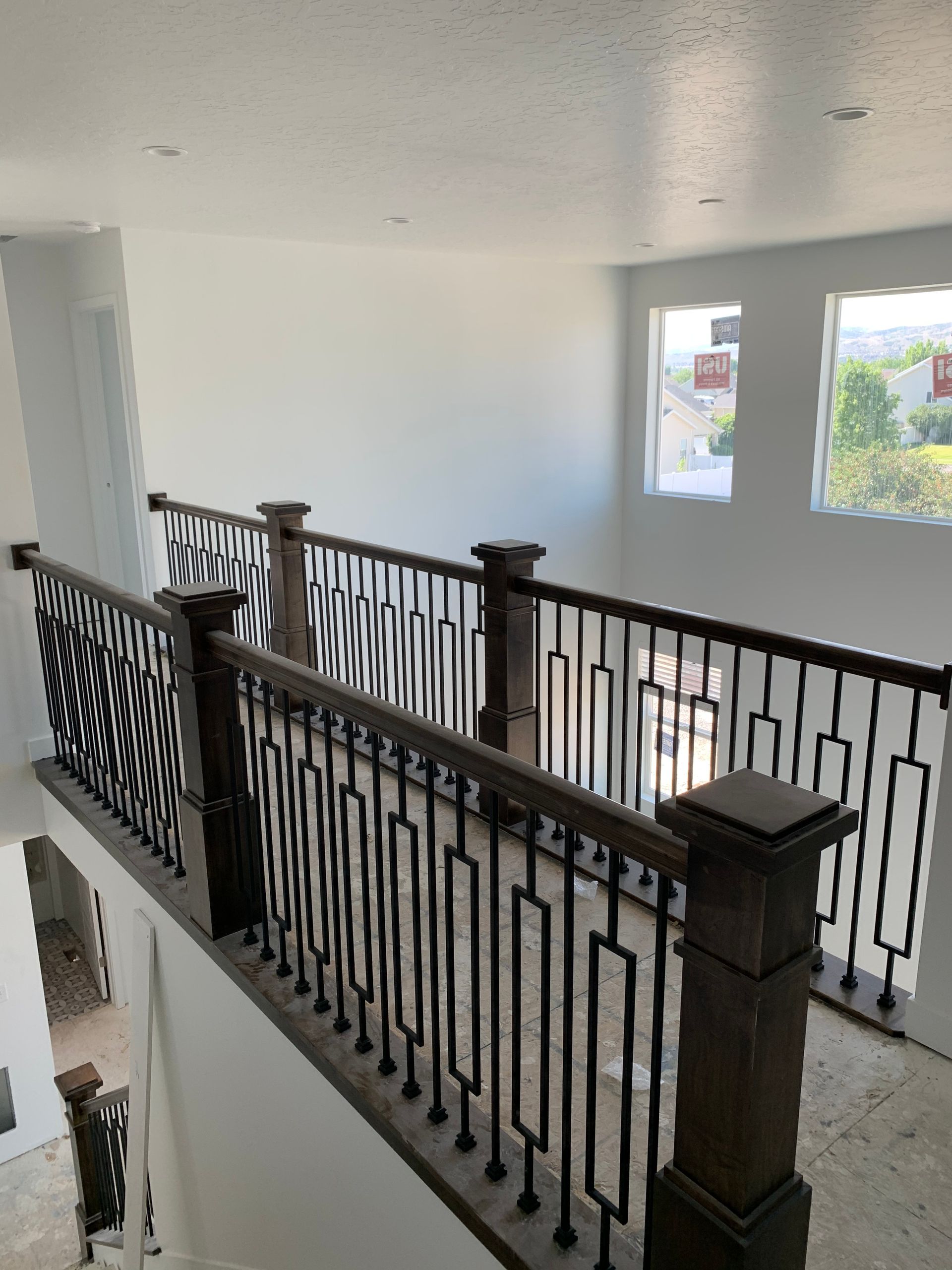 Interior view of a second-floor hallway with a decorative railing and windows looking outside.