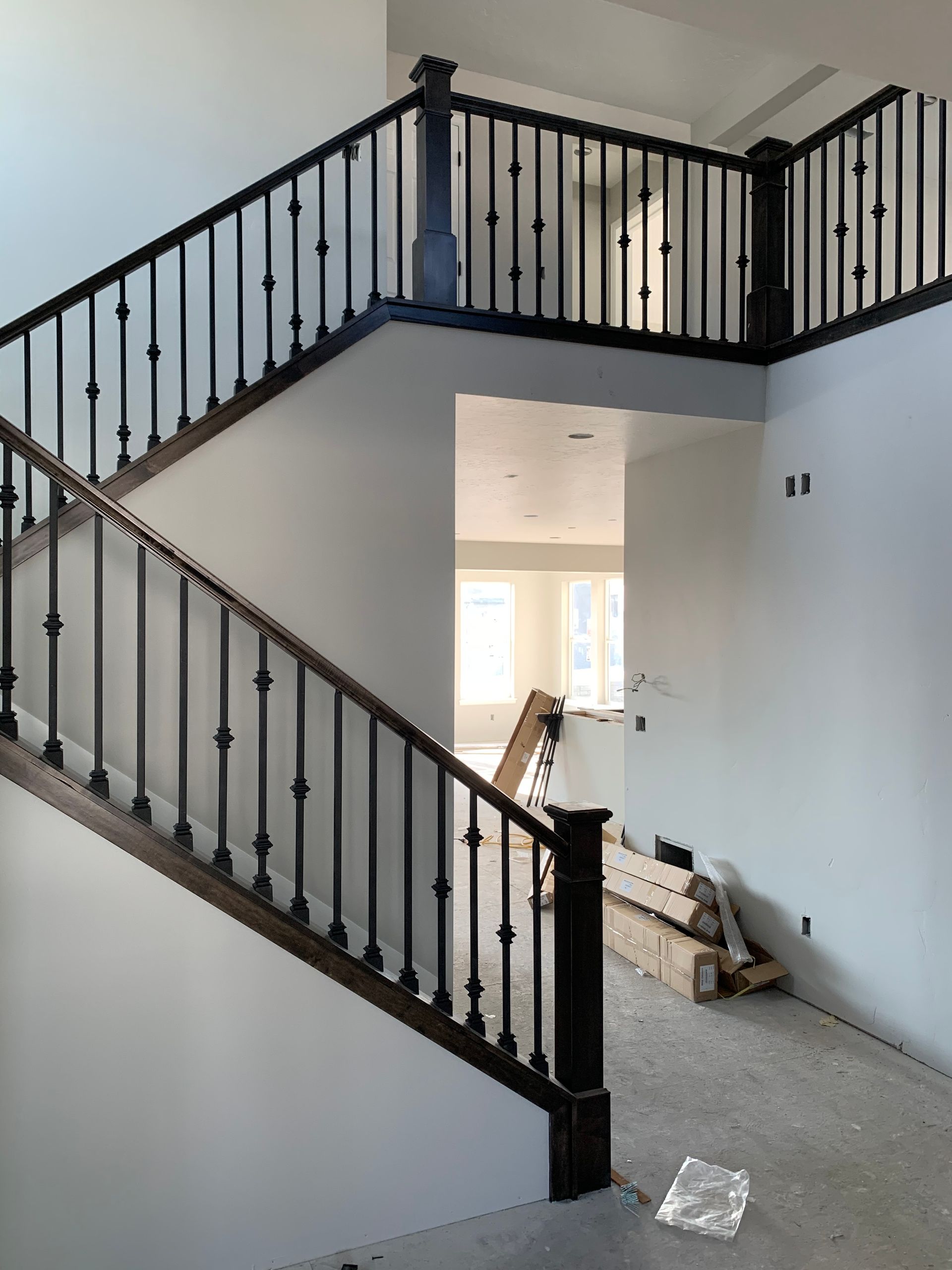 Two-story staircase with dark wood railings and balusters, leading to an open second floor.