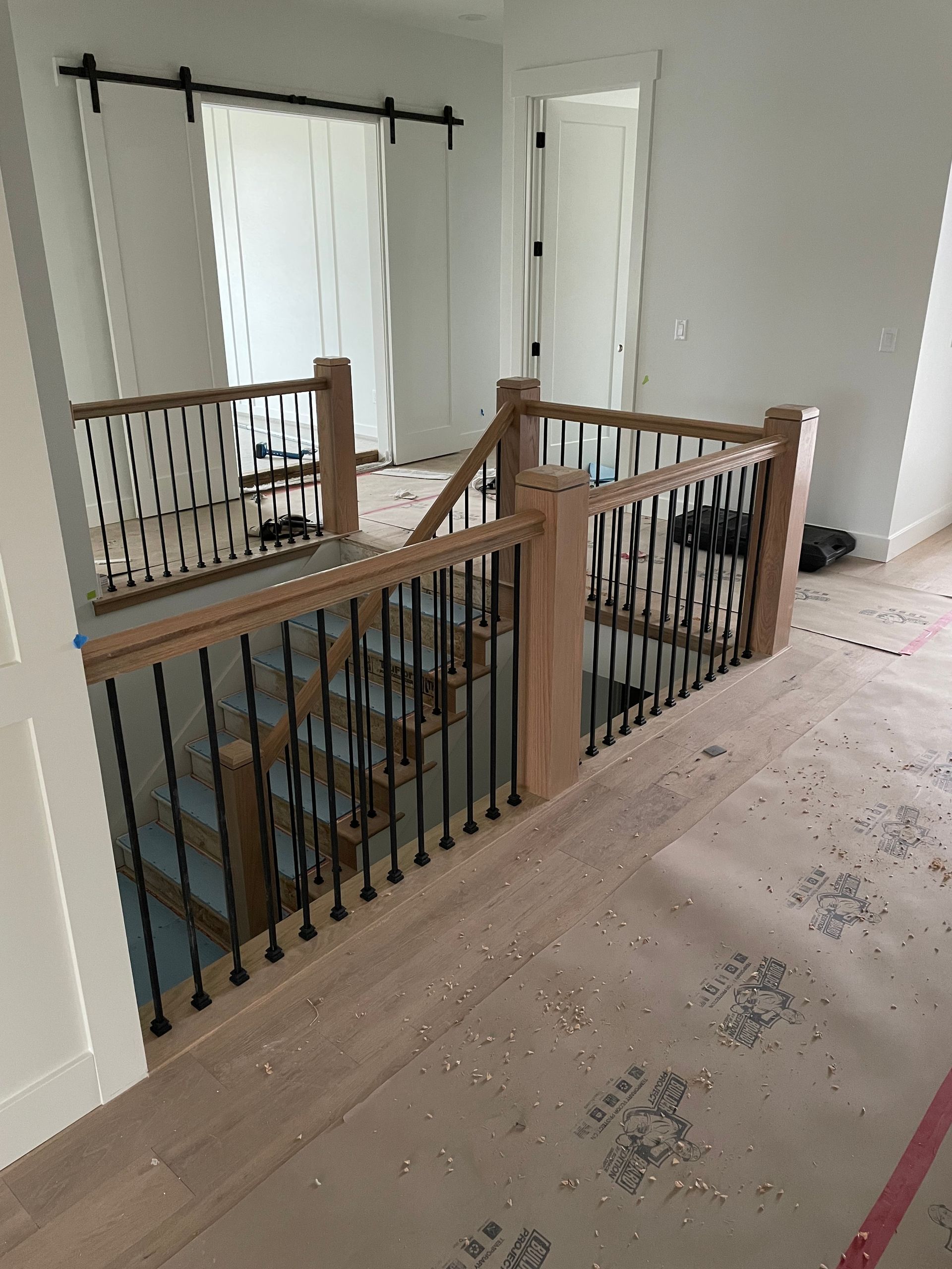 Interior staircase with wooden railings and black spindles; room is under construction.