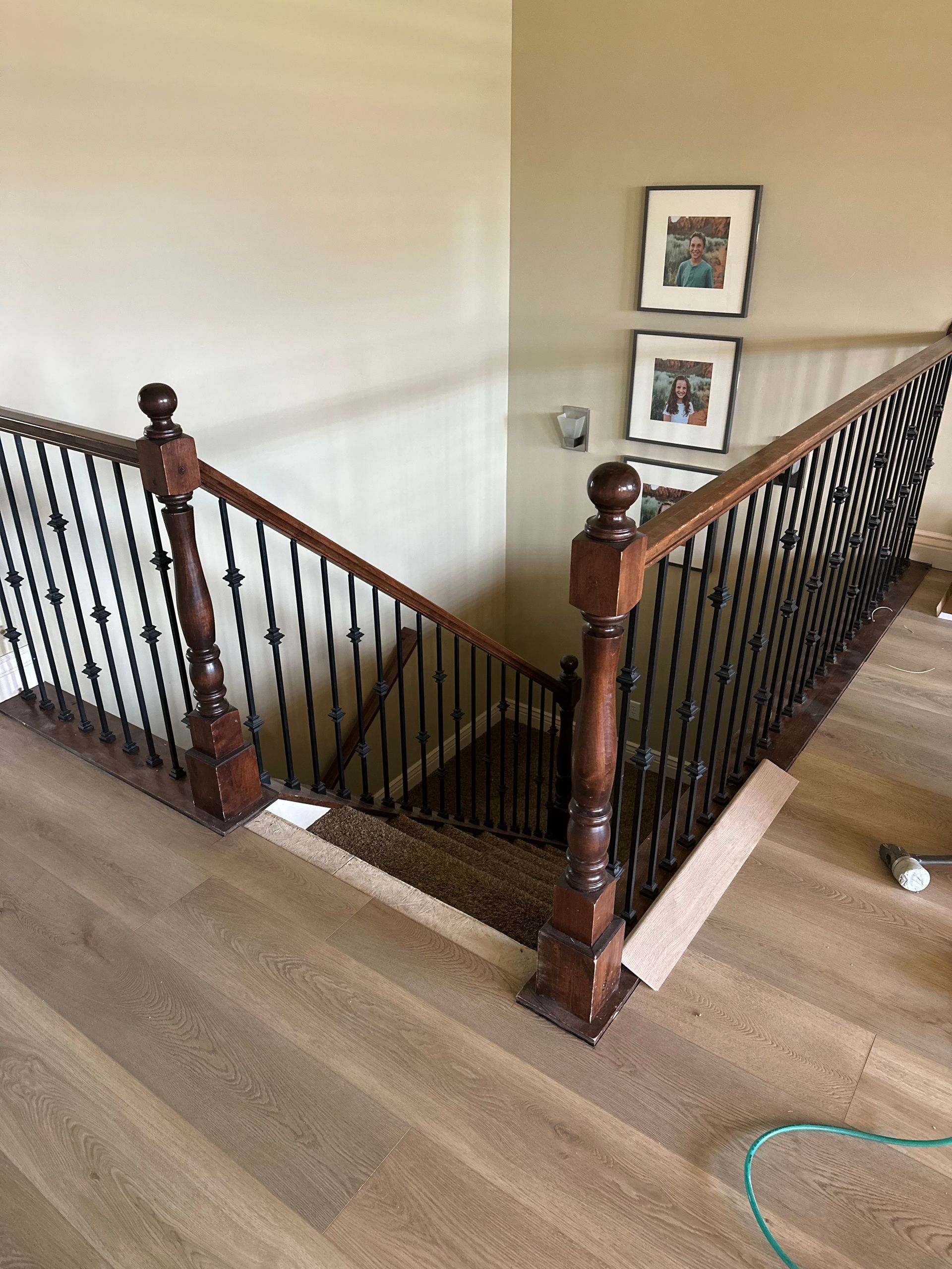 Staircase with wooden handrails and black metal balusters descending to a lower level.