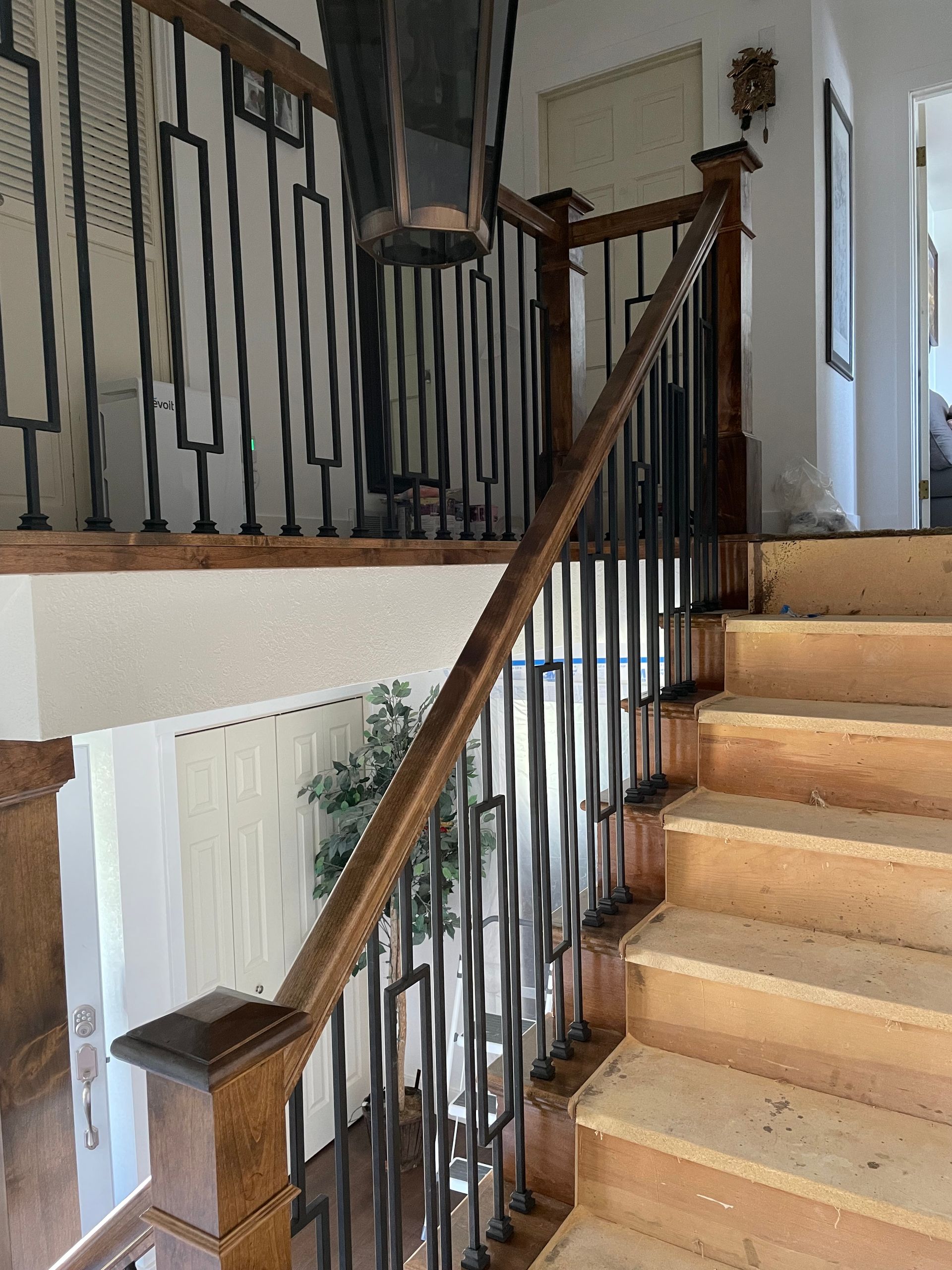 Wooden staircase with black metal railings, leading up to a landing.