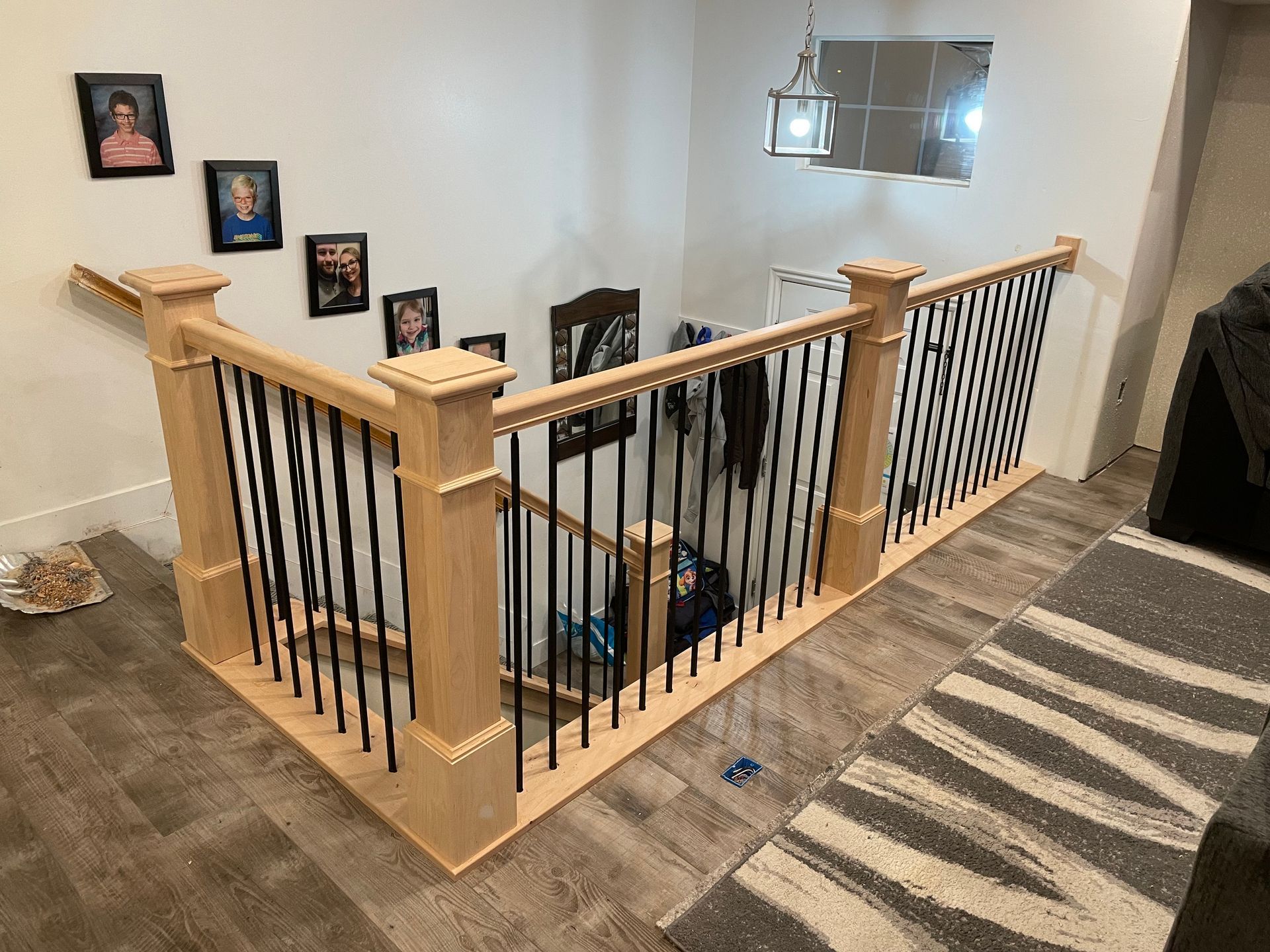 Wooden staircase with black metal spindles and framed photos on the wall.