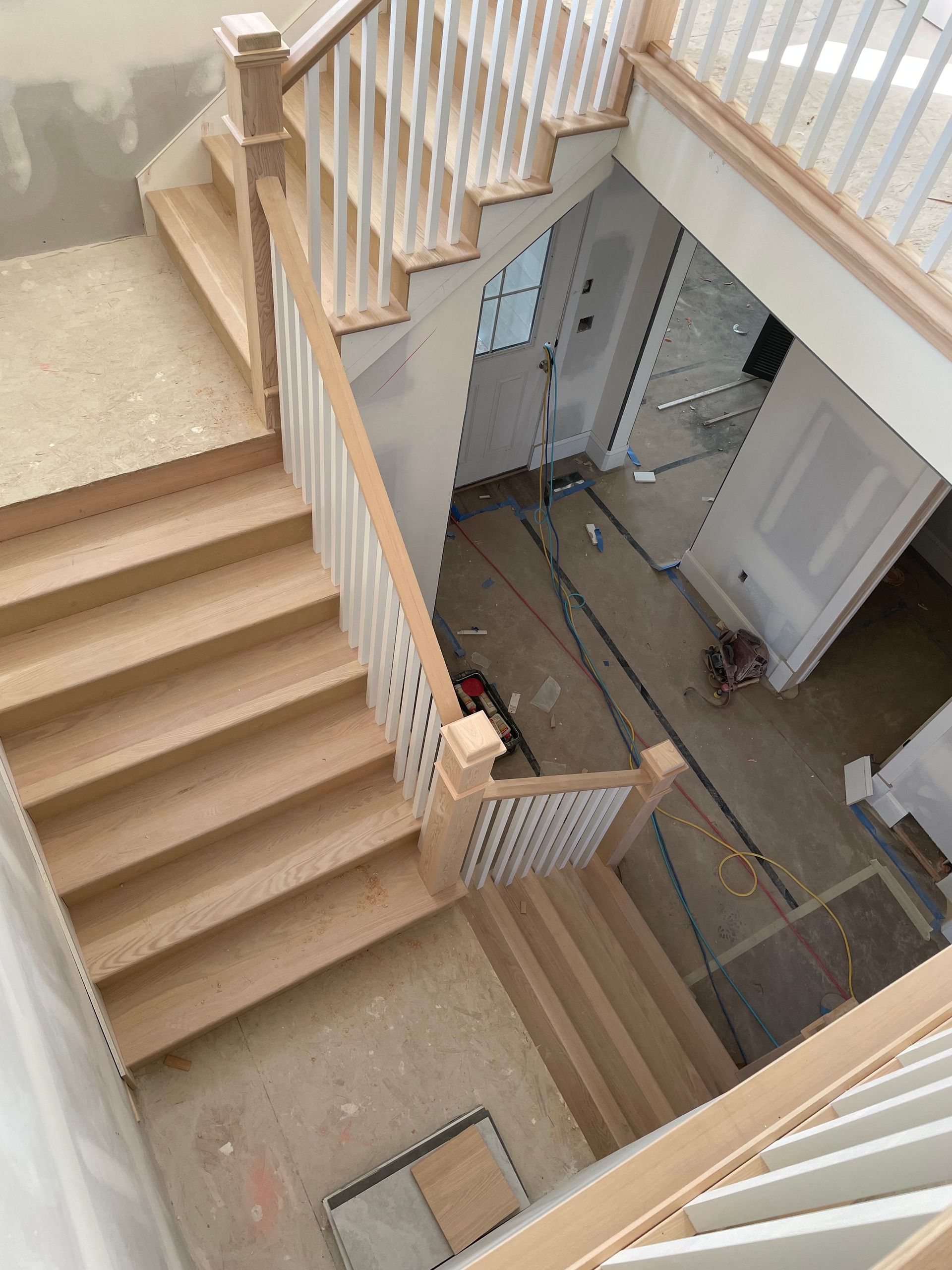 Wooden staircase with white banisters and unfinished construction.