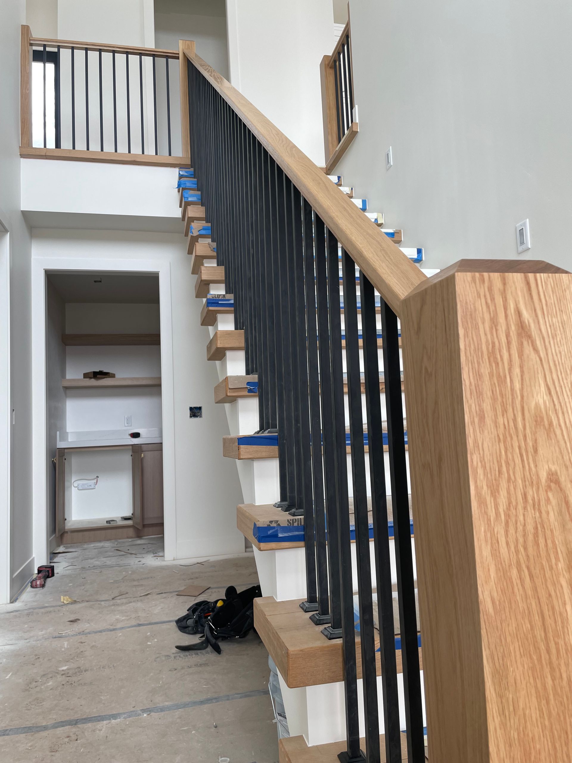 Staircase with wood and black metal railing, leading to an upper level. Interior setting.