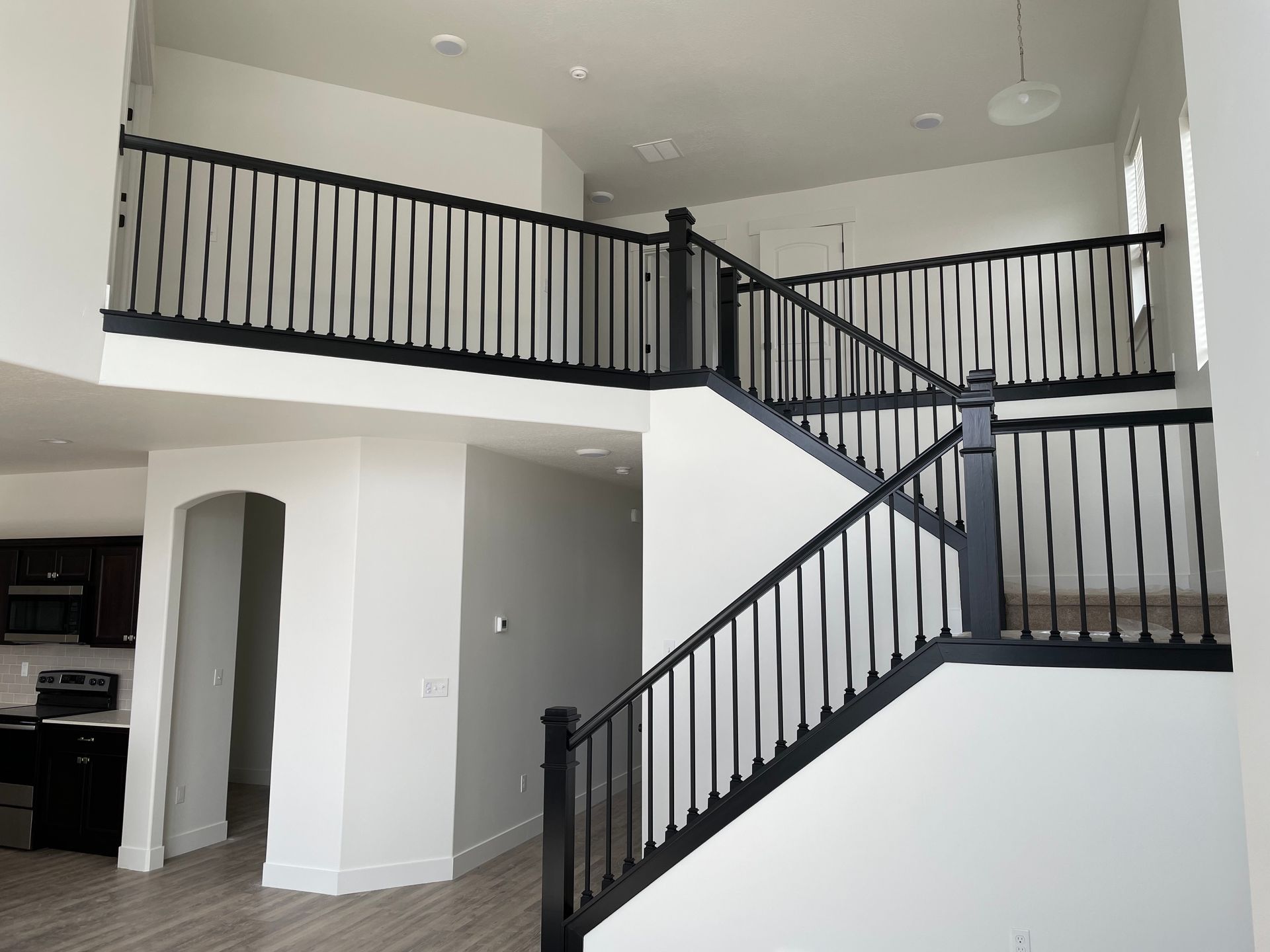 Interior view of a two-story home with a staircase, black railings, and white walls.