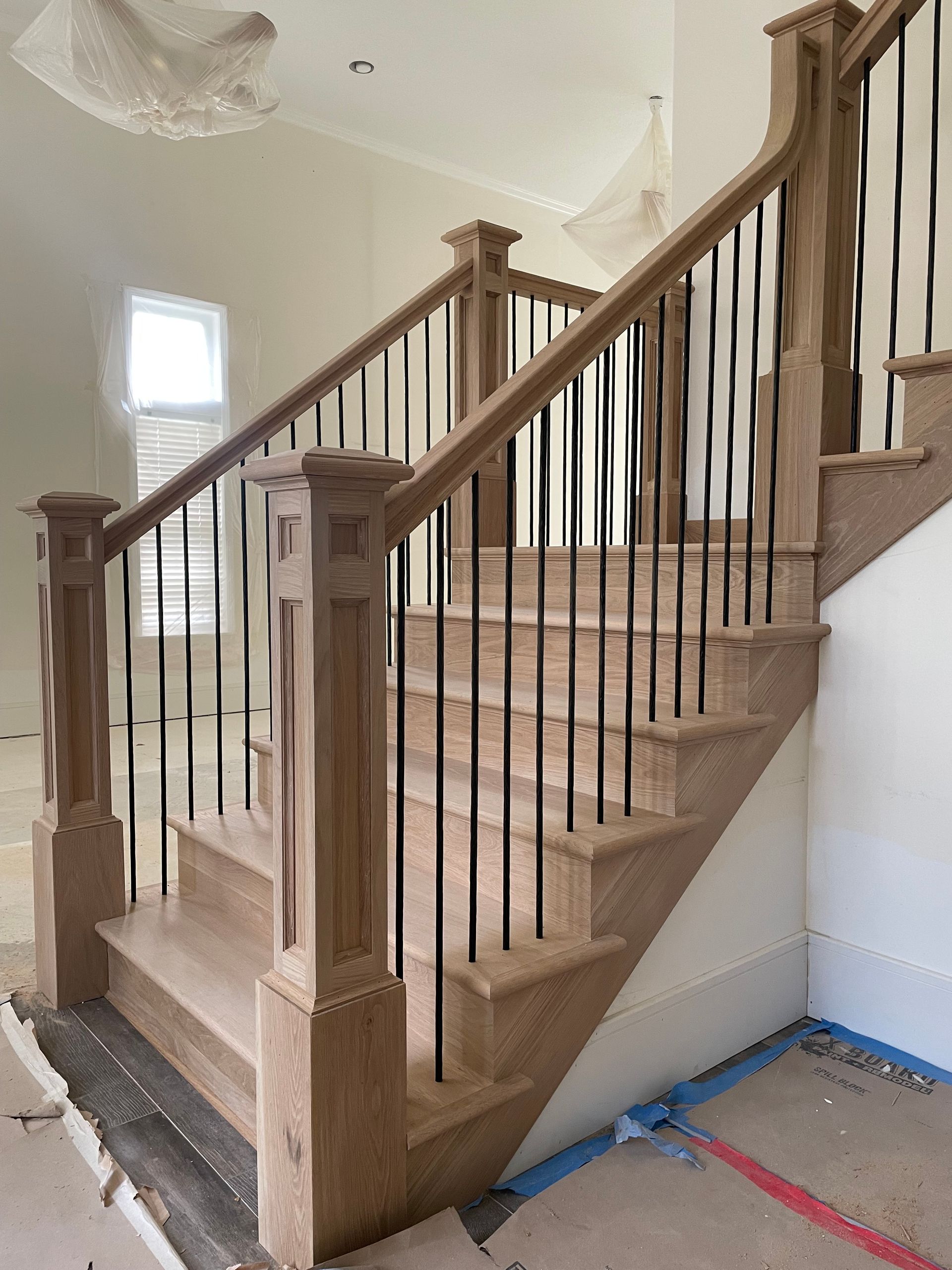 Wooden staircase with black spindles and light wood railing.