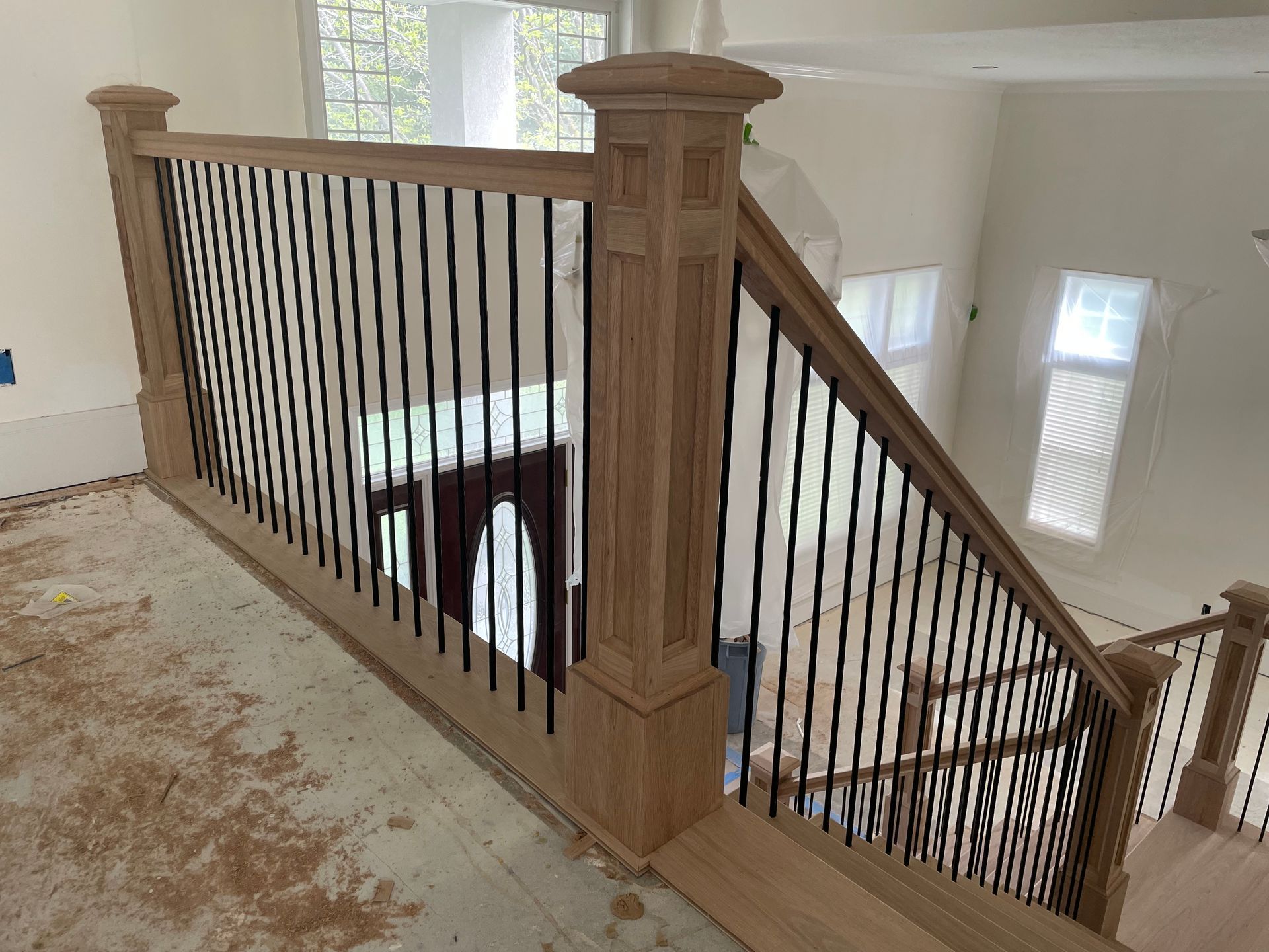 Wooden staircase with black metal balusters, viewed from above.