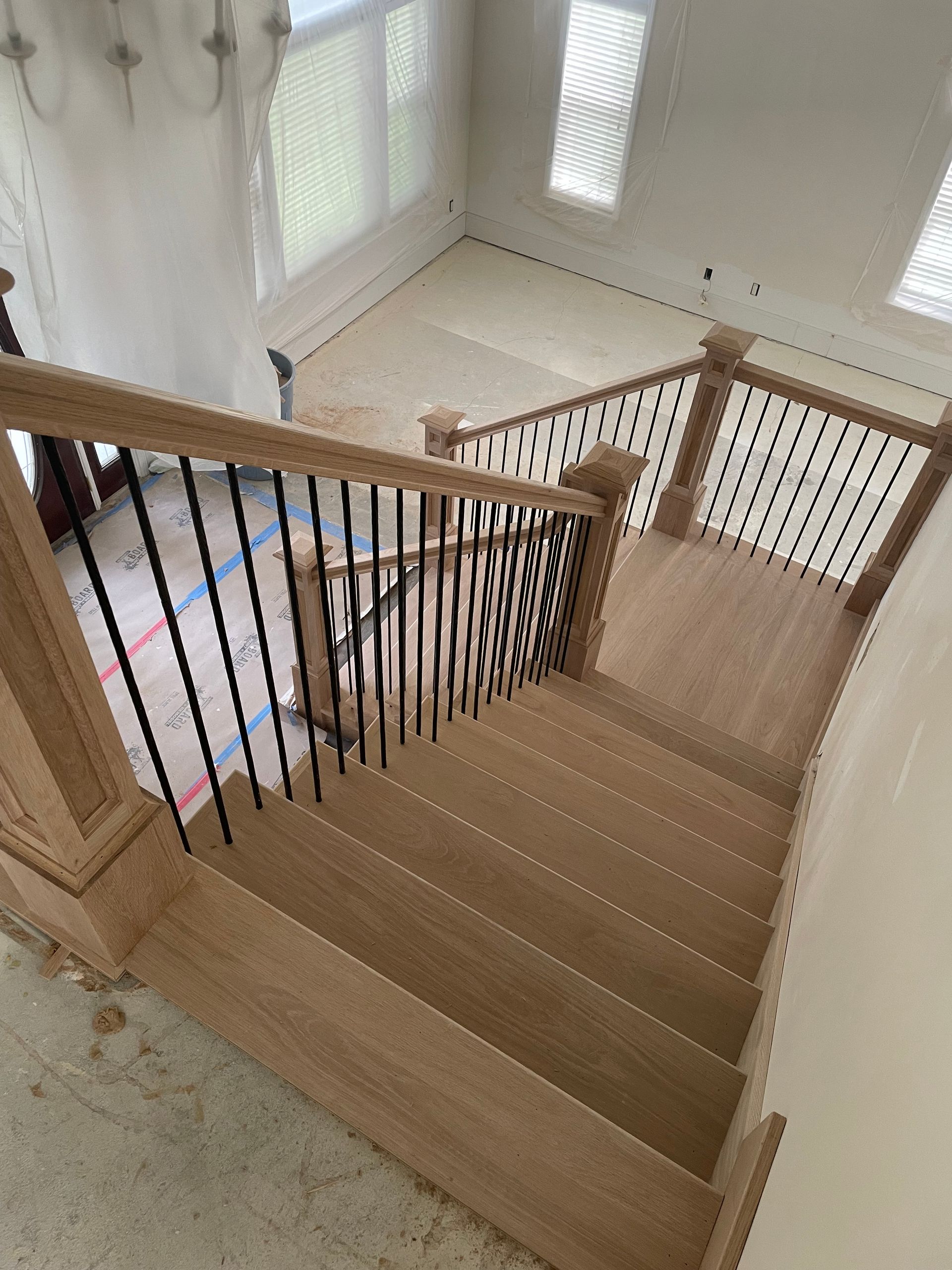 Wooden staircase with black metal balusters, viewed from above.