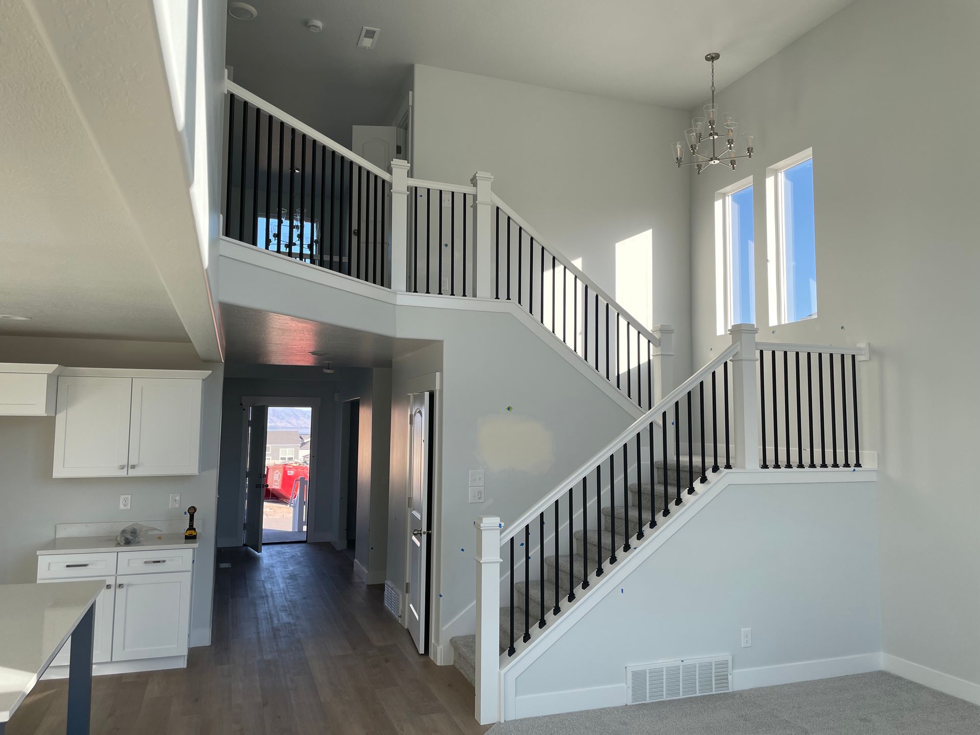 Spacious, light-filled two-story entryway with a staircase featuring black railings and white balusters.
