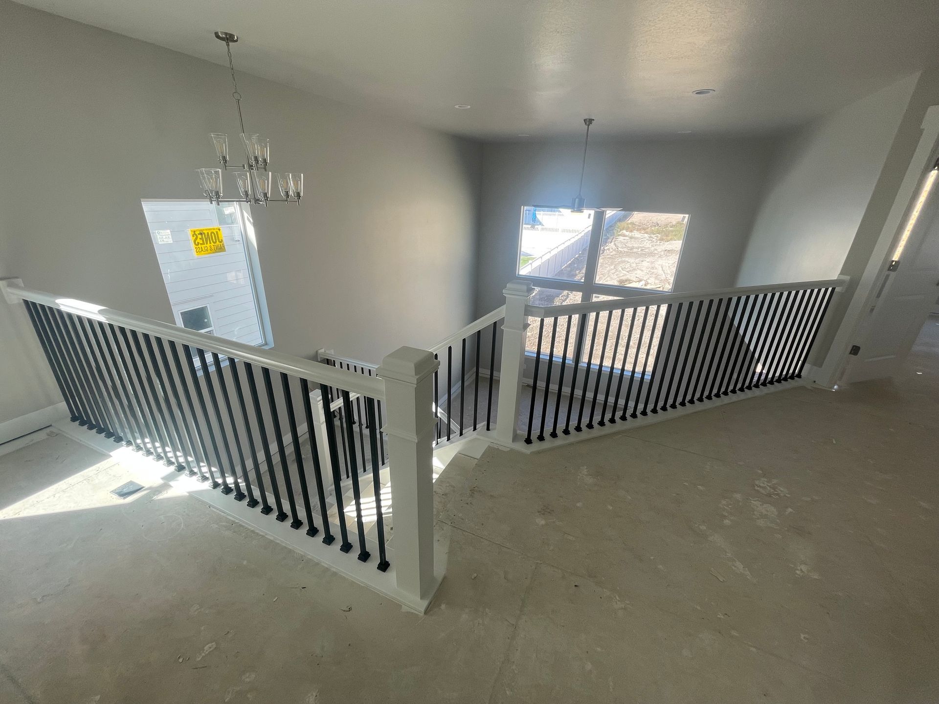 Interior view of a staircase with white railing and black spindles, with a light fixture above.