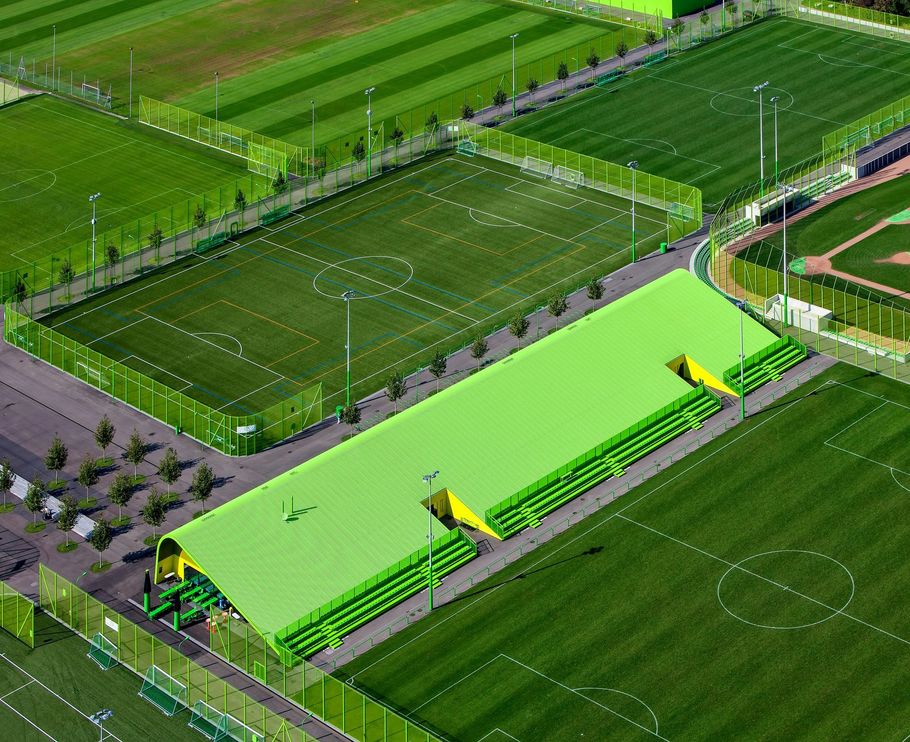 Aerial view of a soccer field with bright green covered stands and surrounding athletic fields.