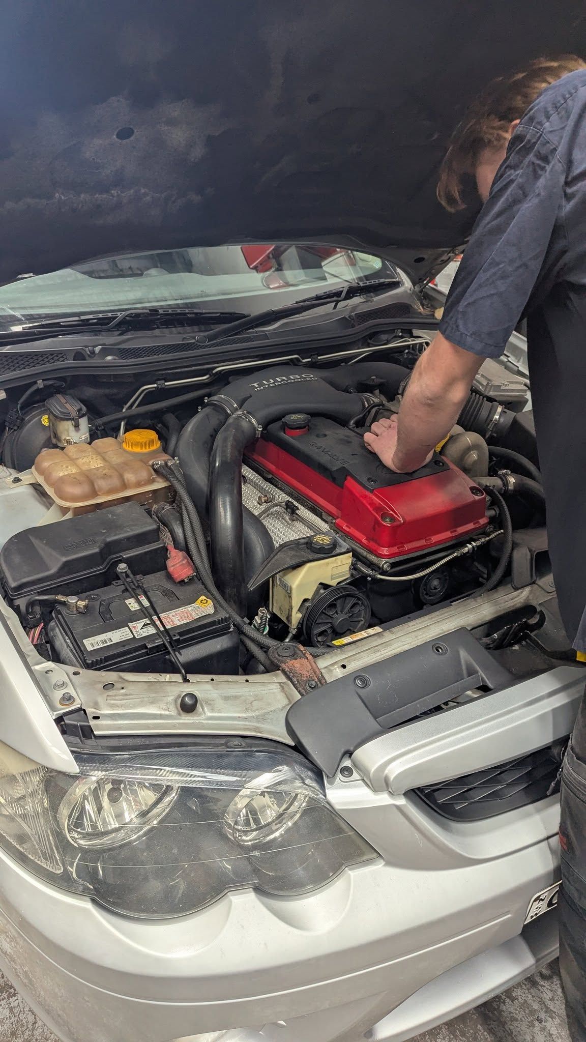Person Working on A Silver Car's Engine, Hood Open — ATD Automotive in North Wollongong, NSW