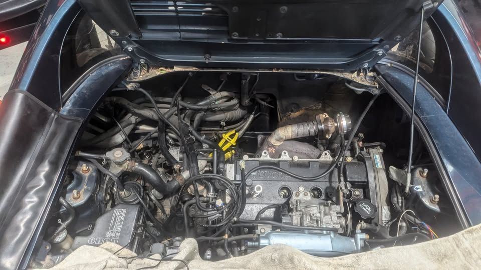 Engine compartment of a black car, filled with machinery, wiring, and tubes, under an open hood — ATD Automotive in North Wollongong, NSW