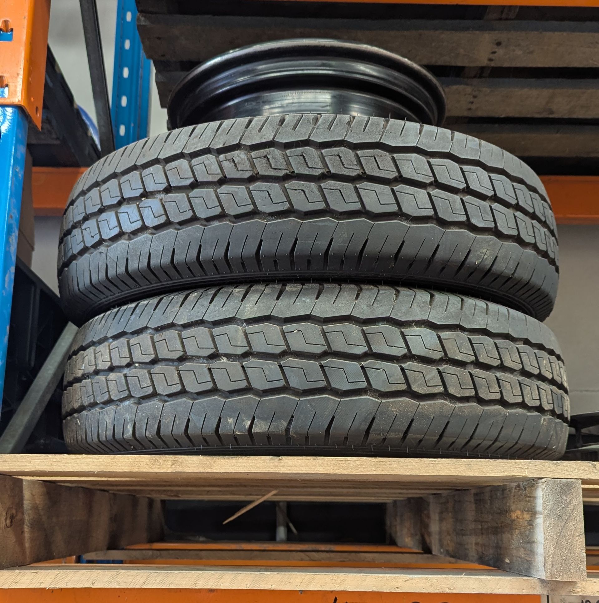 Two tires stacked on a wooden pallet with a black wheel on top in a warehouse setting  — ATD Automotive in North Wollongong, NSW