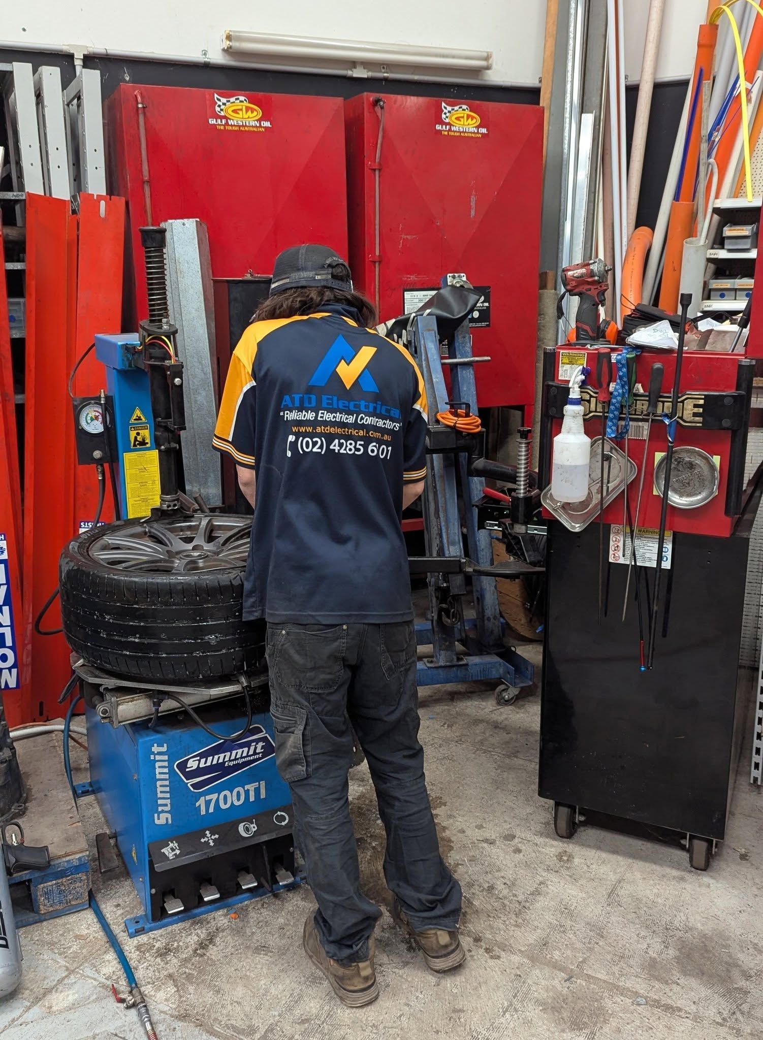 Mechanic Working on A Tire in A Garage. Blue and Red Machines — ATD Automotive in North Wollongong, NSW
