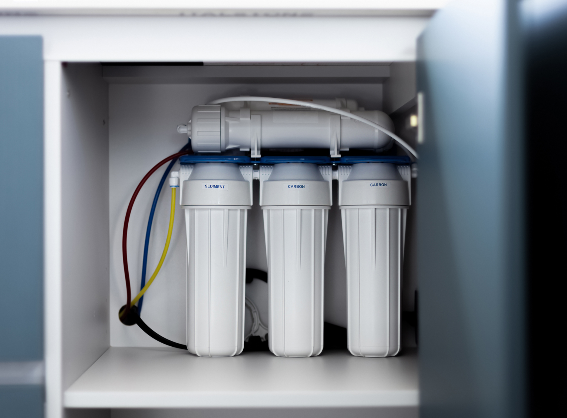 A water filter is sitting inside of a cabinet.