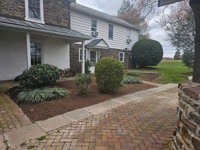 There is a brick walkway leading to the front of the house.