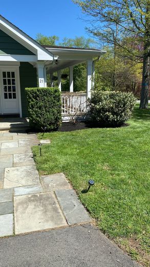 A house with a stone walkway leading to it and a lush green lawn.