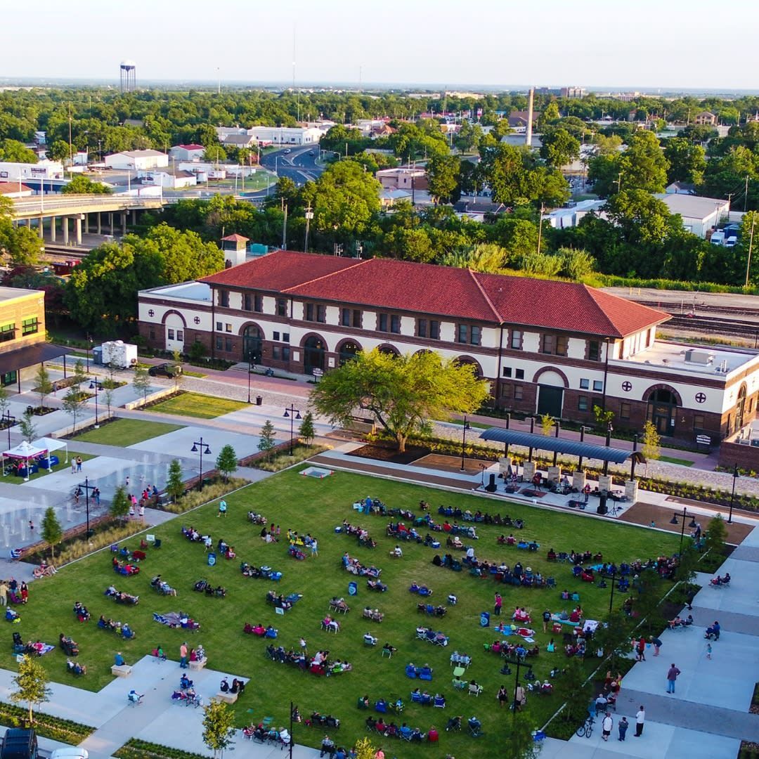 First Friday block party in downtown Temple, TX with crowds, live music, food vendors, and string lights at dusk