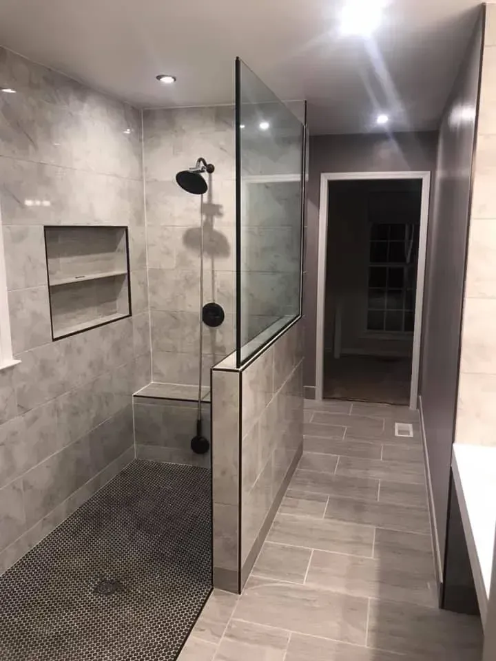 A bathroom with a walk in shower and a glass door.