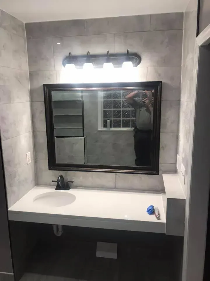 A bathroom with a sink , mirror and light fixture.