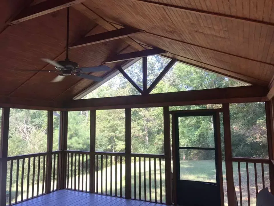 A screened in porch with a ceiling fan