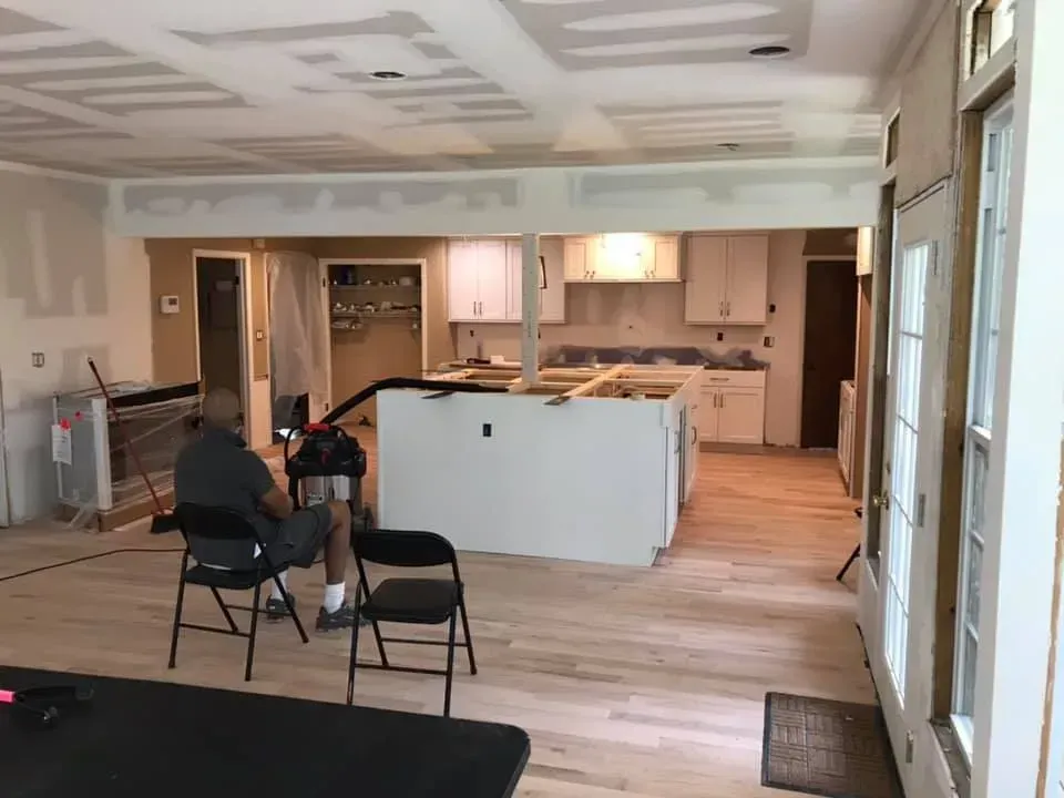 A man is sitting in a chair in a kitchen under construction.
