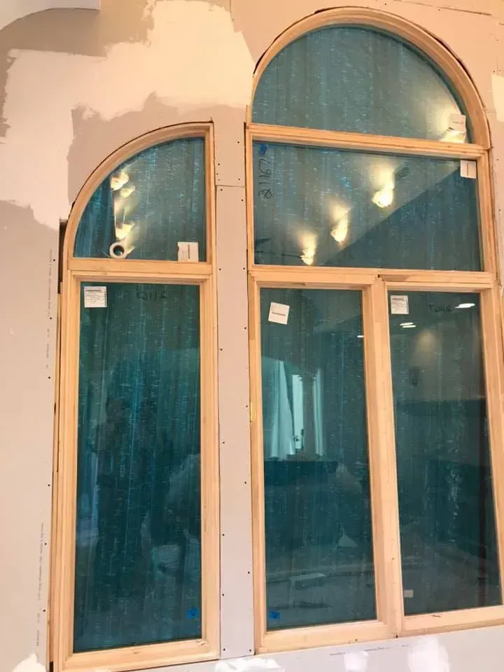 Two arched windows are being installed on a wall