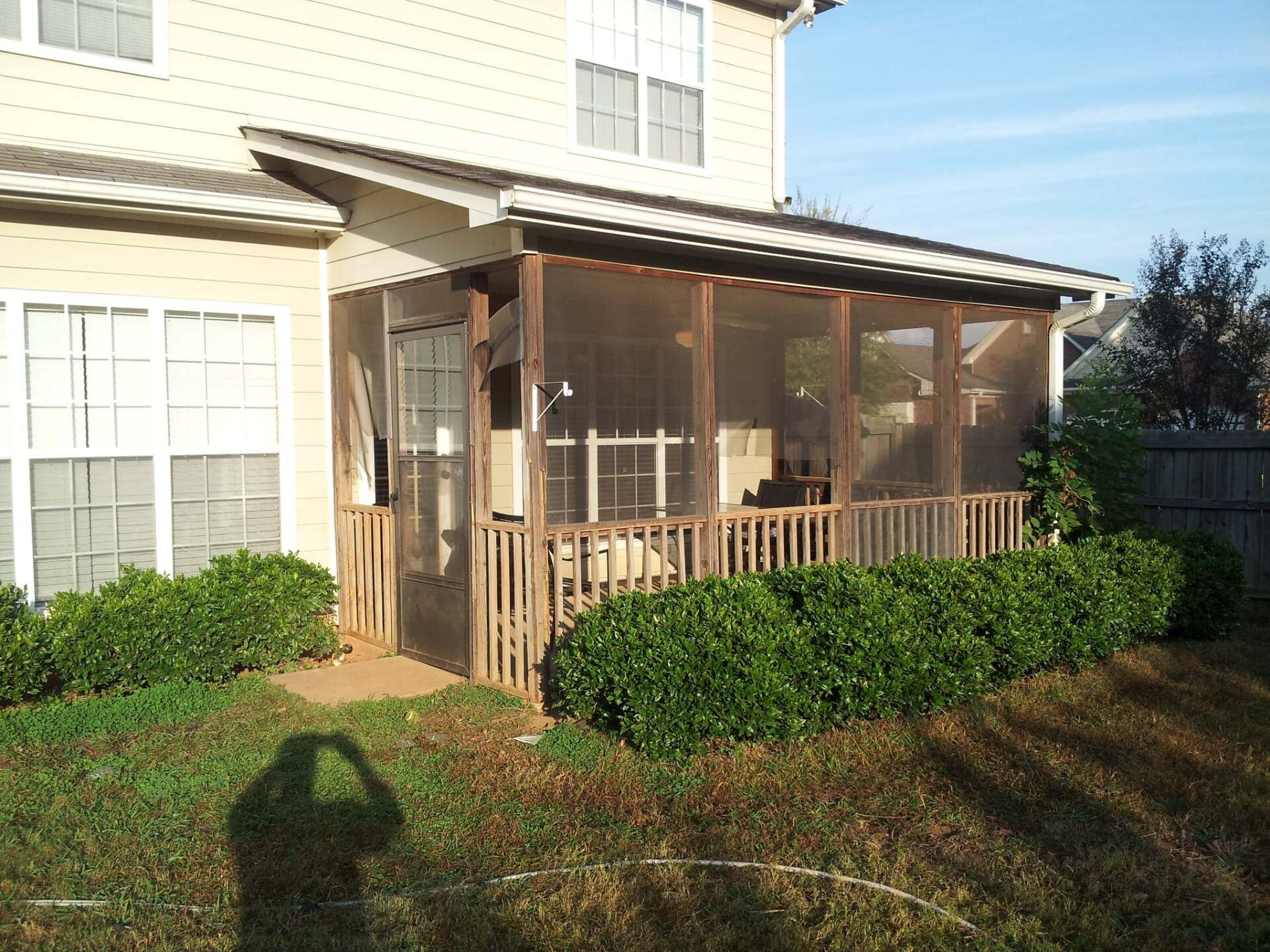 A screened in porch in the backyard of a house