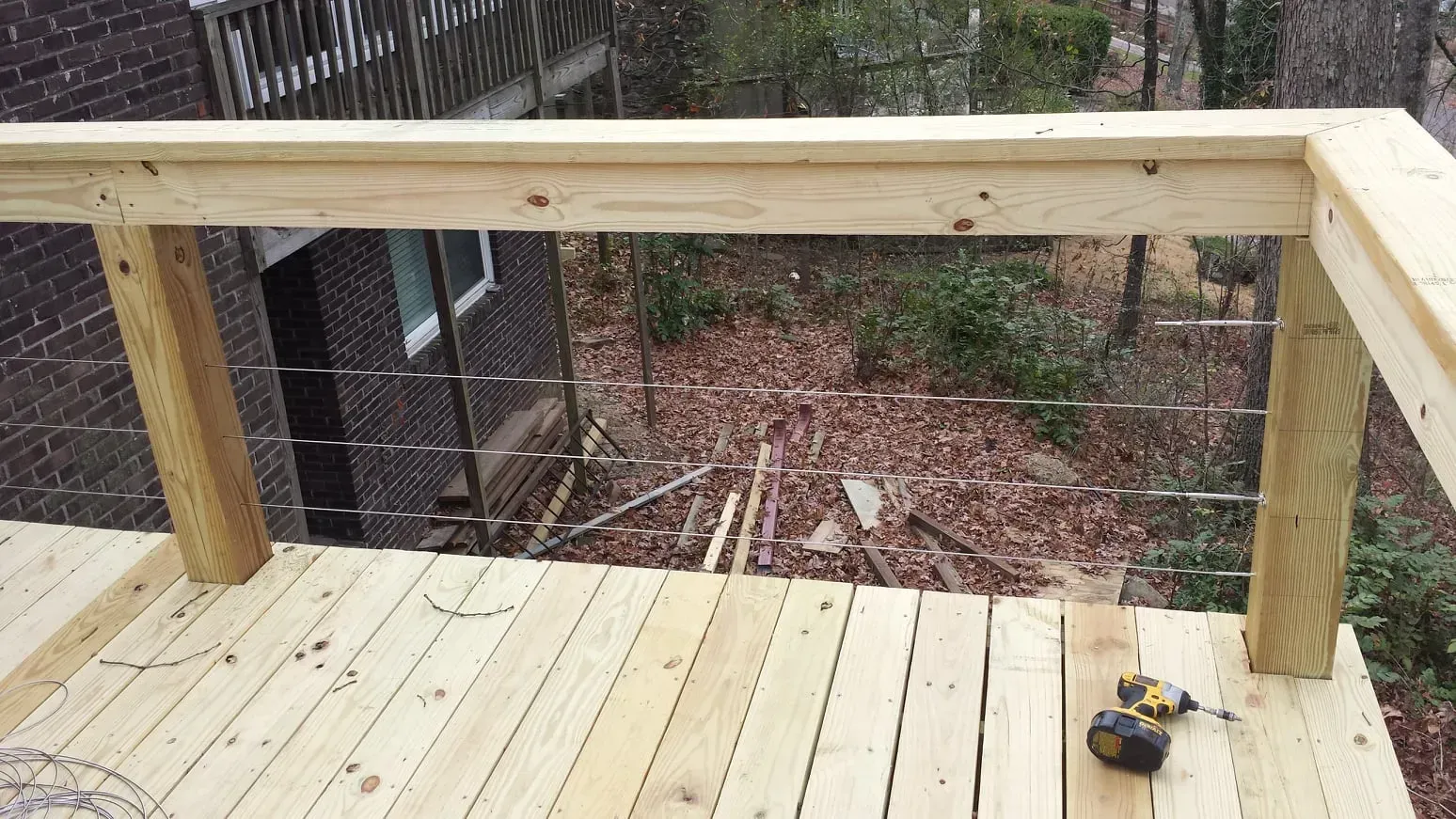 A wooden deck with a stainless steel railing is being built.