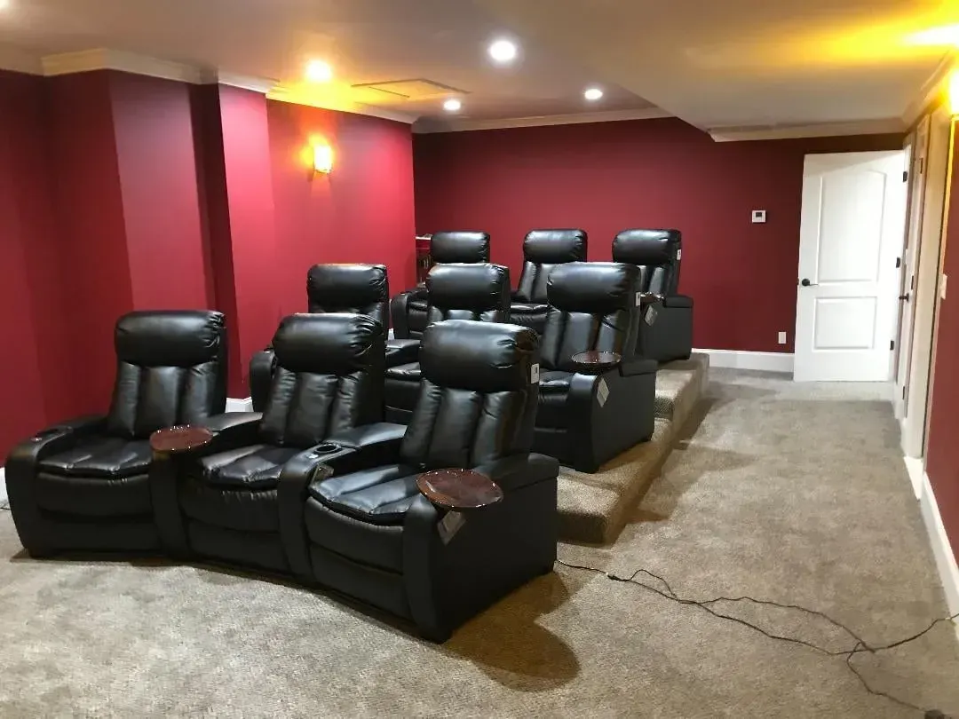 A home theater with black leather chairs and red walls.