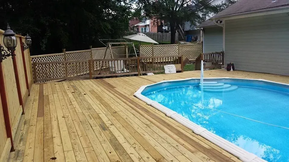 A large swimming pool is surrounded by a wooden deck.